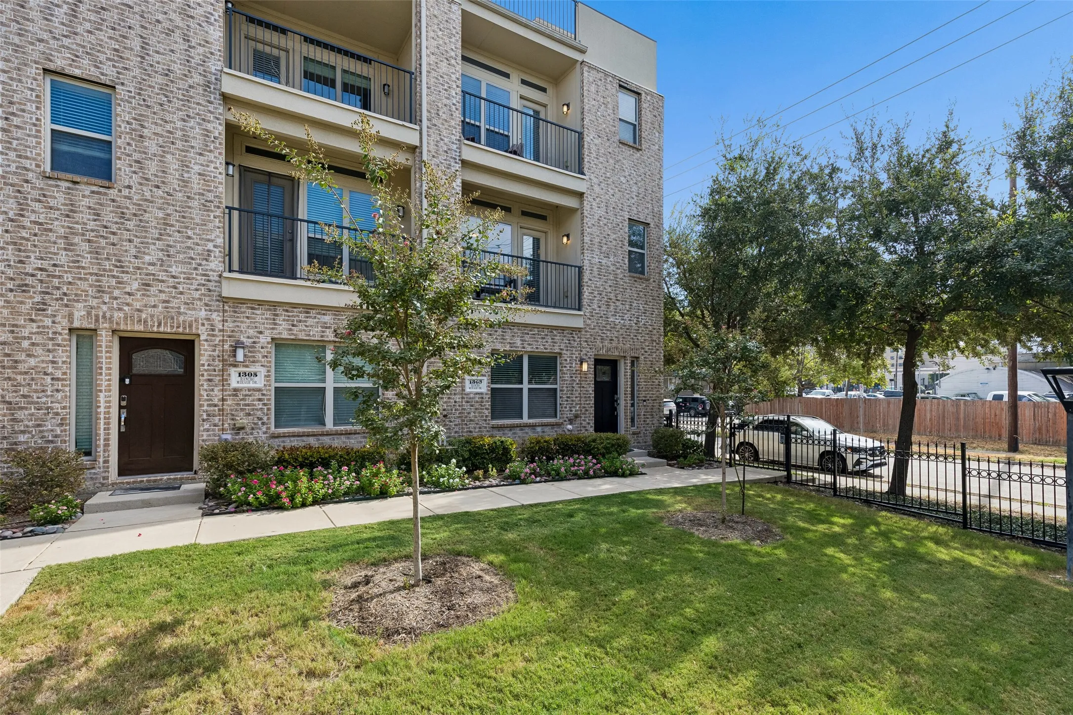Multi-level brick exterior with multiple balconies and a manicured lawn