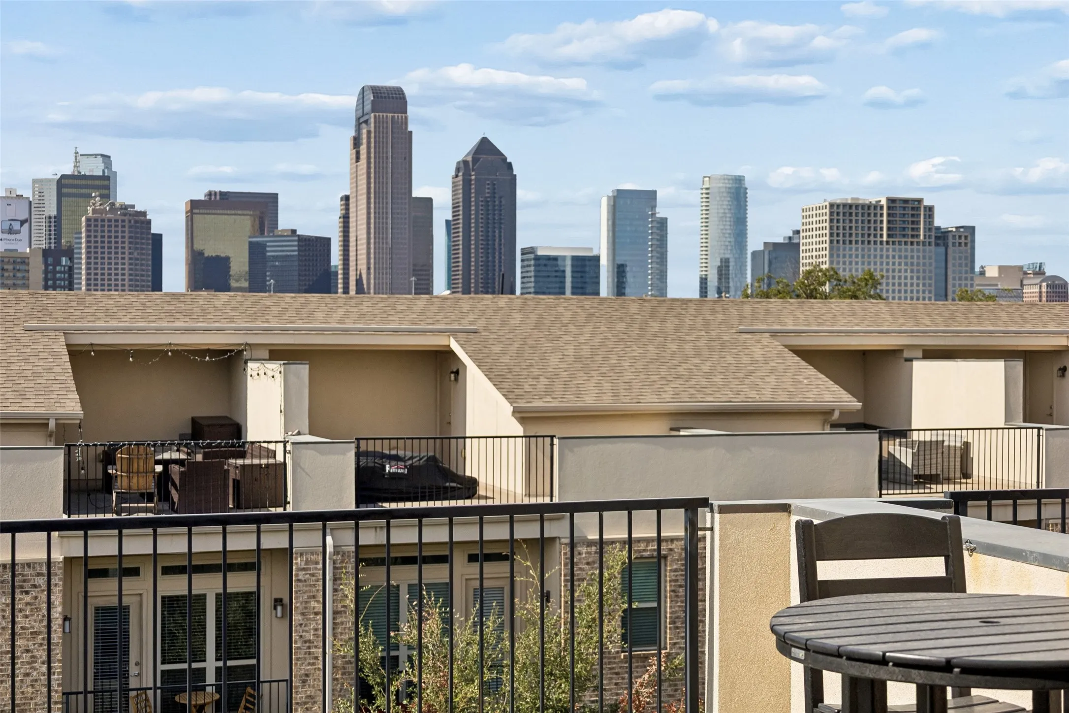 Expansive rooftop terrace with black metal railings, a stucco exterior, and a visible downtown skyline