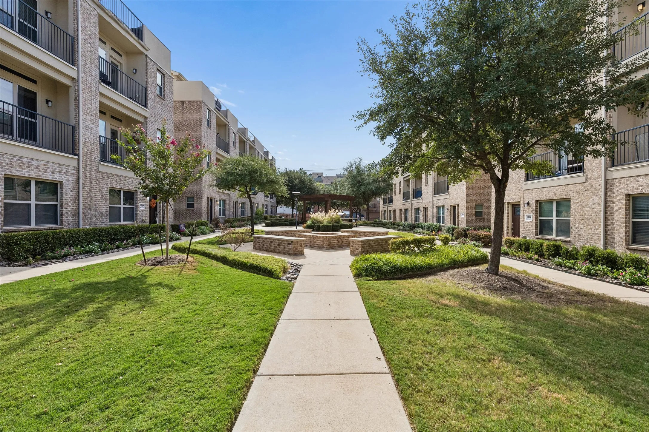 Central courtyard featuring structured landscaping, concrete walkways, and mature trees
