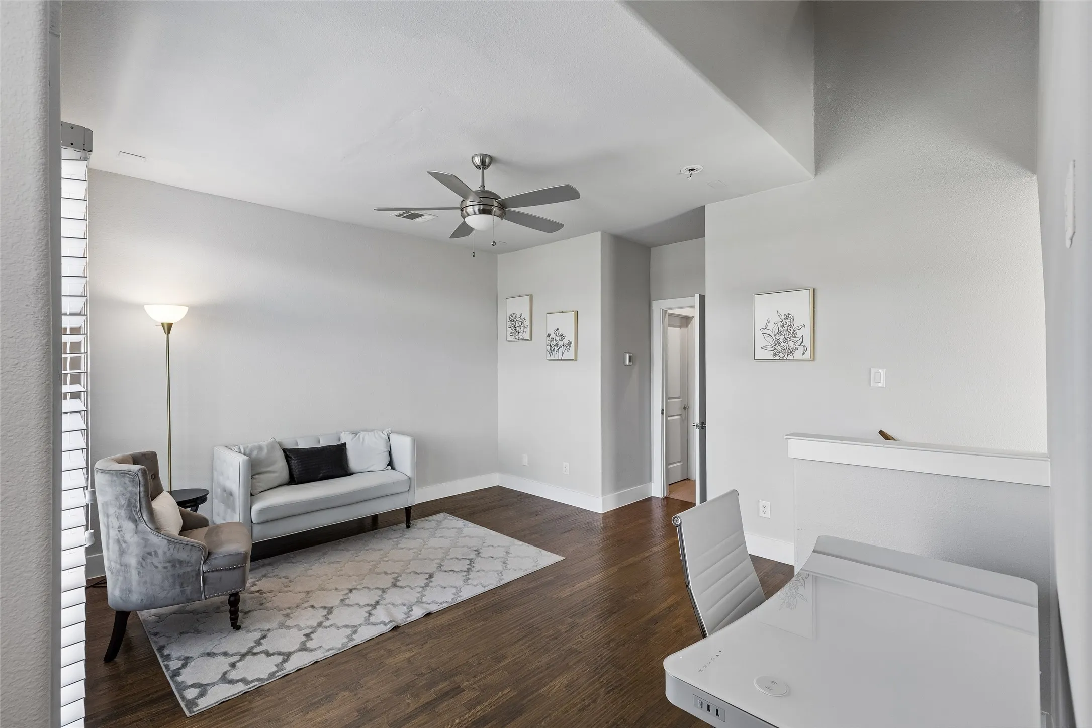 Hardwood-finish flooring, light grey wall paint, and a ceiling fan with integrated lighting
