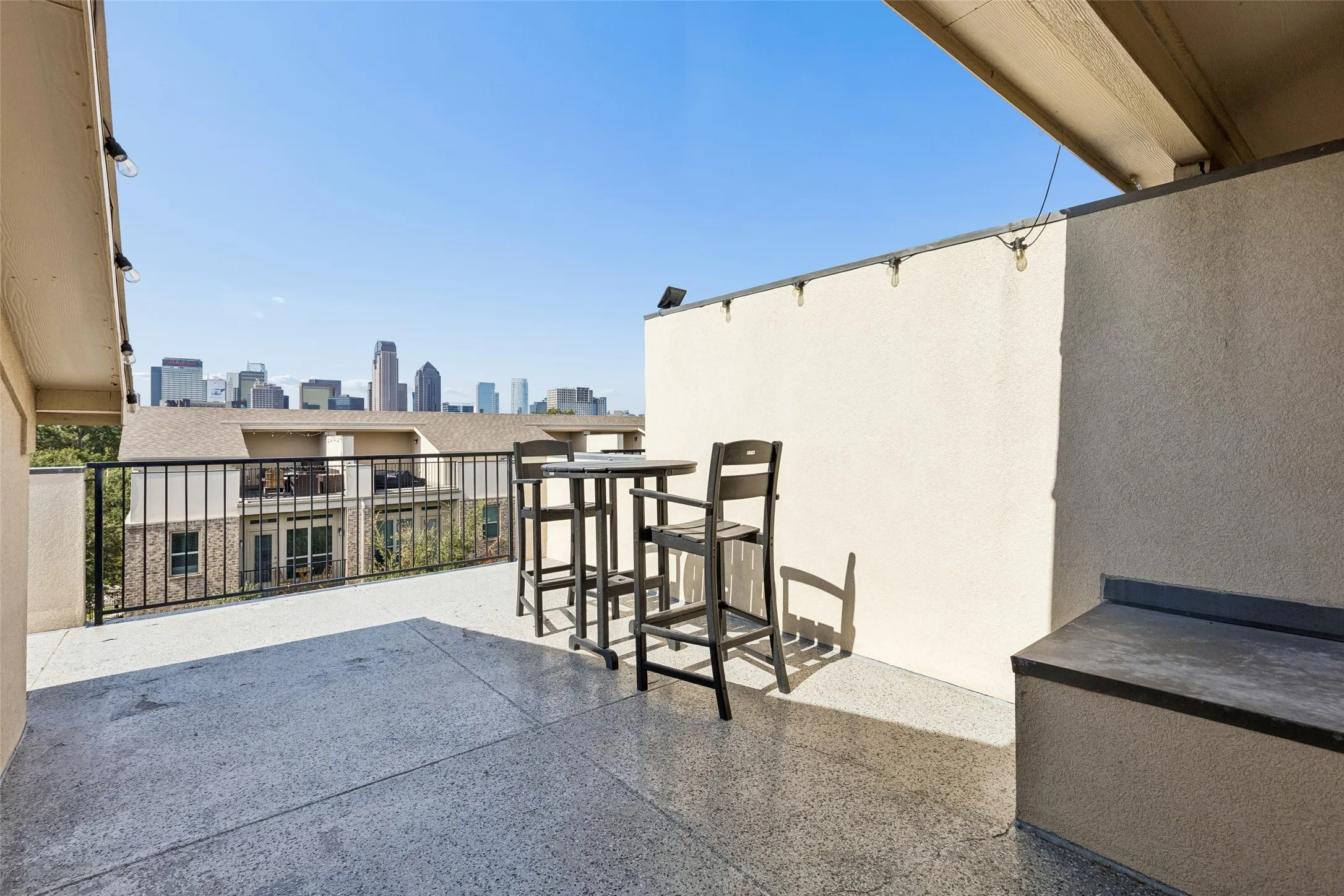 Spacious private balcony with concrete flooring, black metal railing, and a cityscape backdrop