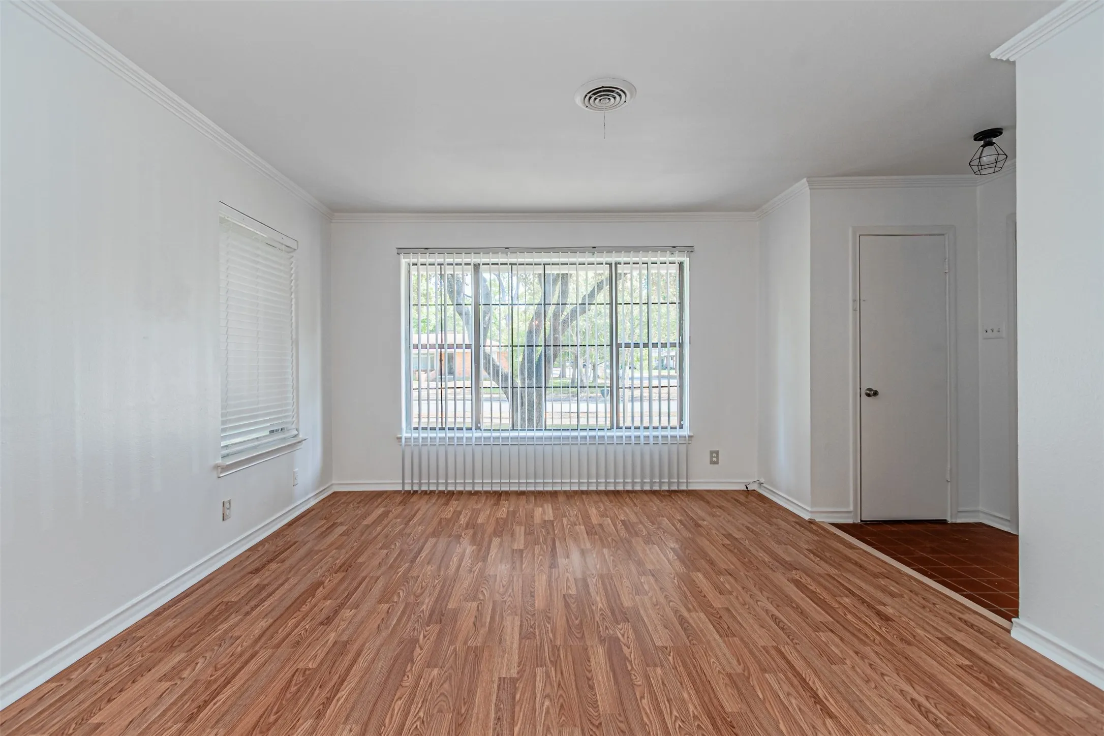 Wood-finish flooring, white walls, and crown molding