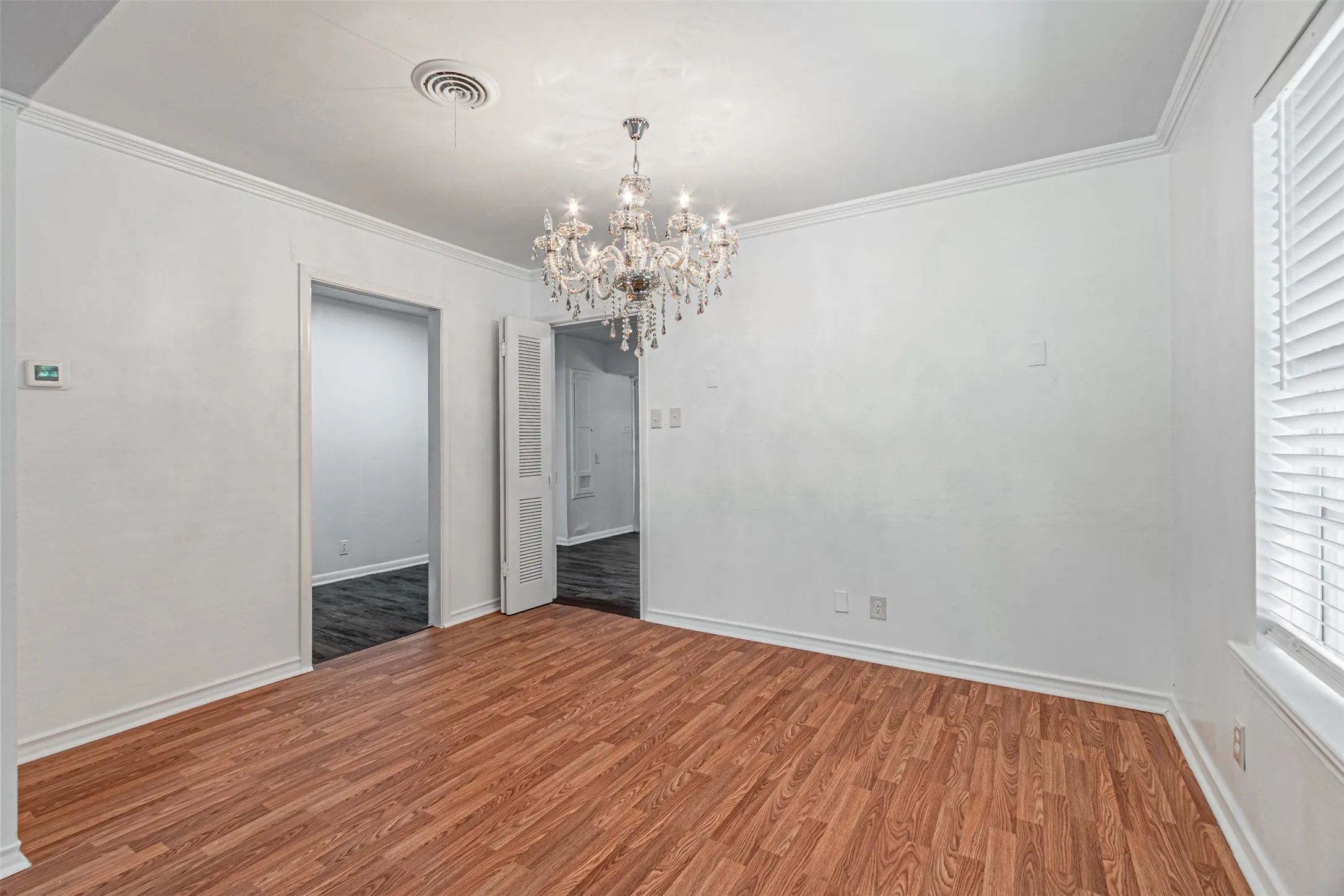 Wood-finish flooring with crisp white walls and crown molding
