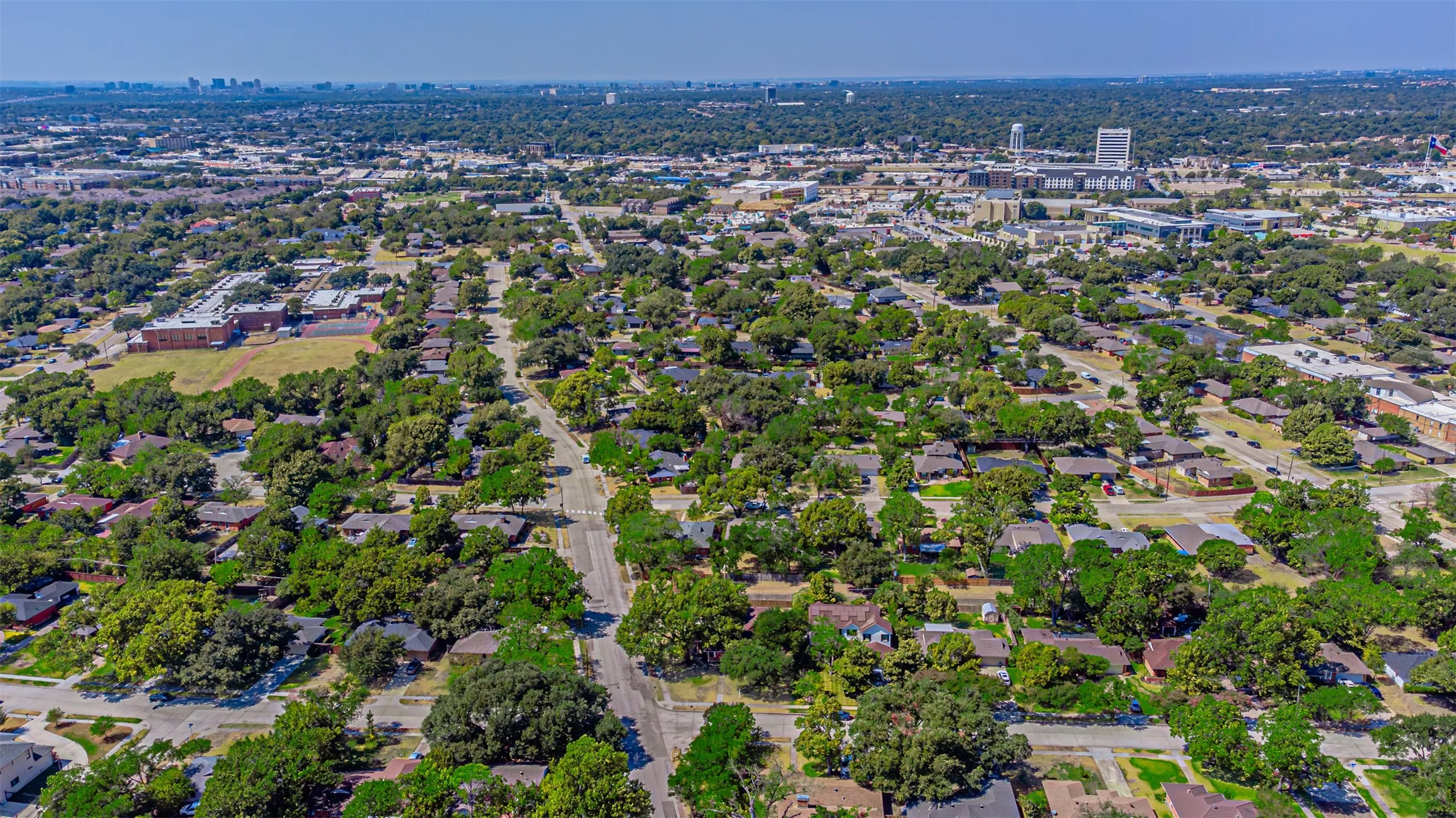 Additional contentThe image is an aerial photograph showing a residential neighborhood with tree-lined streets, single-family homes, and green spaces