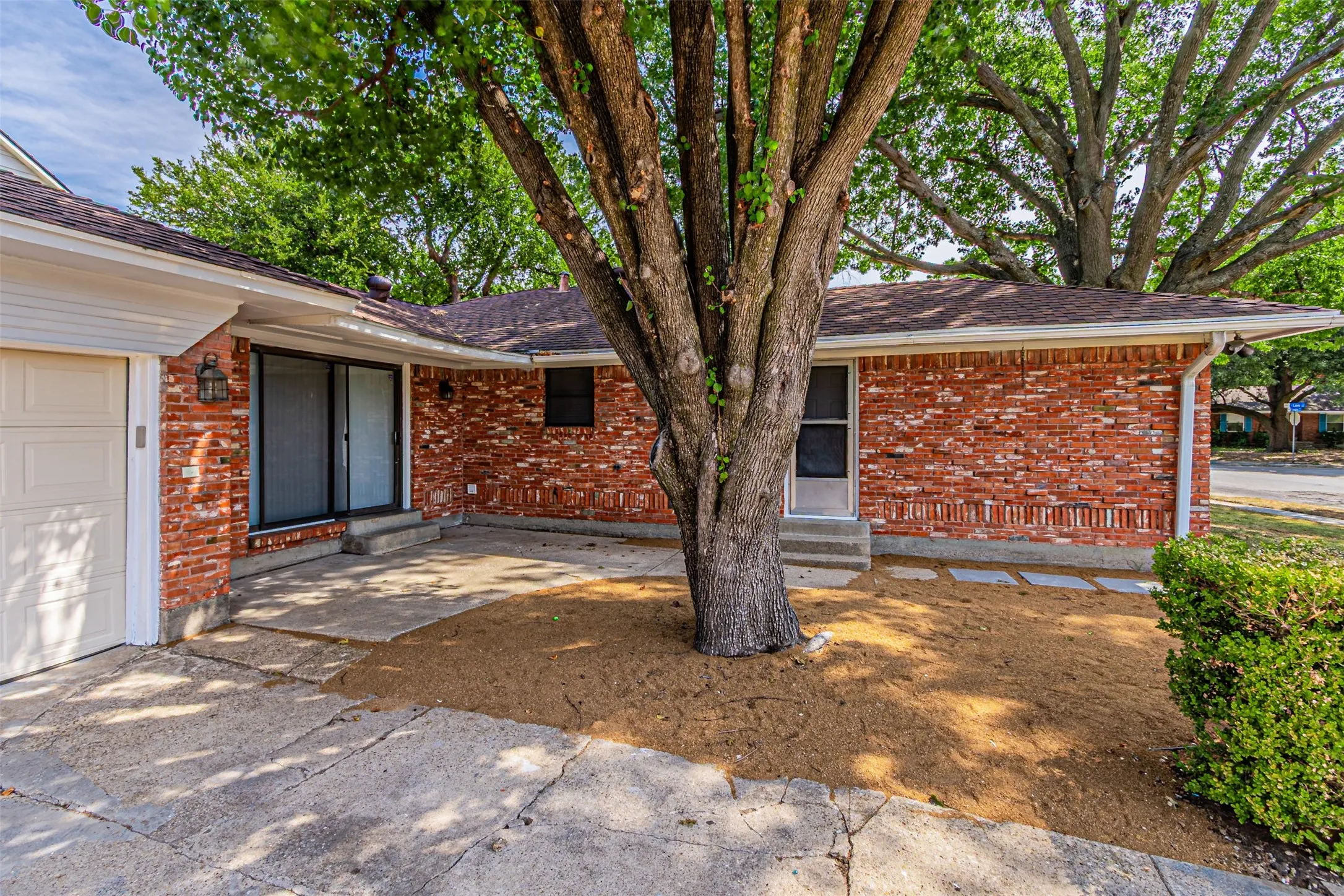 Brick exterior with white gutters, an attached garage, and sliding glass doors
