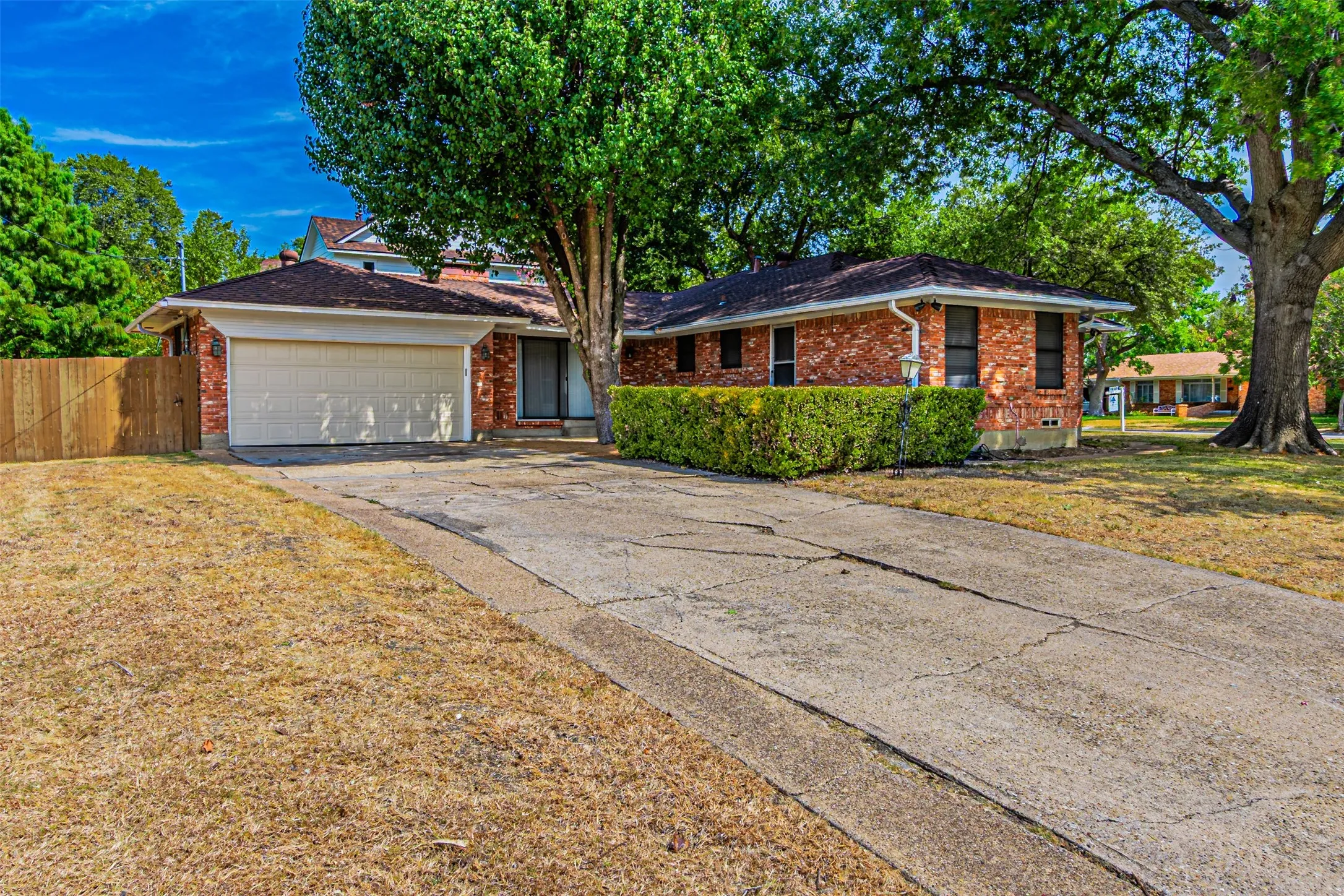 Brick exterior with a partial second story, attached garage, and mature trees