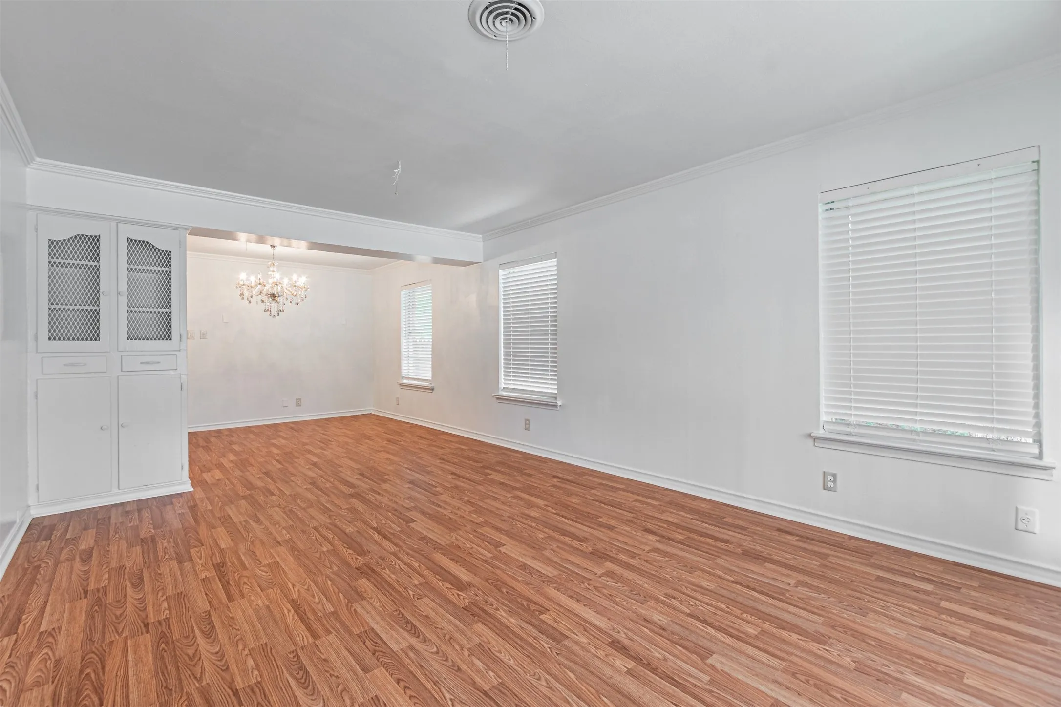 Wood-finish flooring throughout, white walls, and crown molding