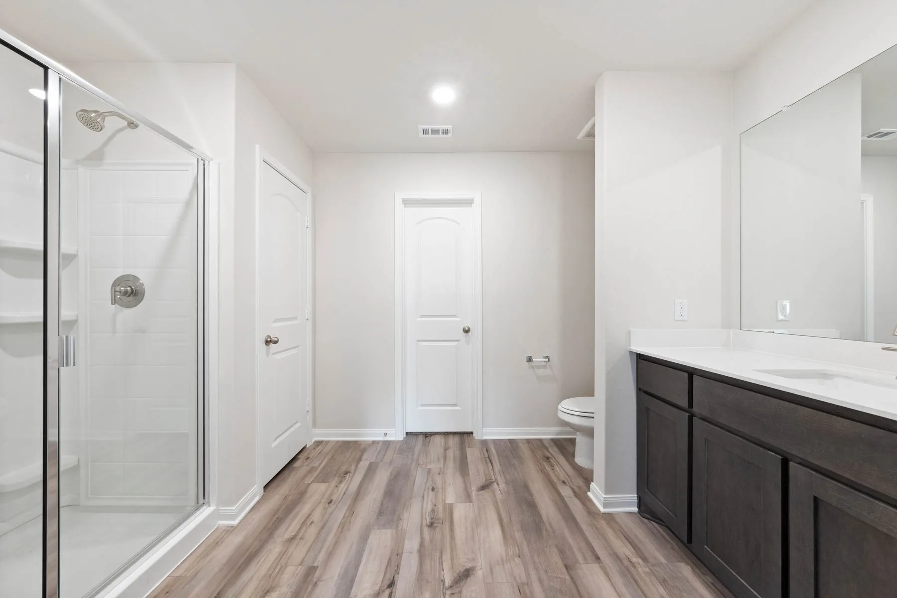 Bathroom with vanity, wood-type flooring, a shower with shower door, and toilet