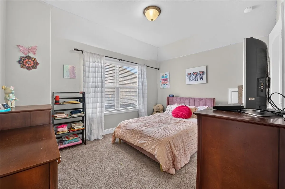 Window with blinds and sheer curtains, tray ceiling, wall-mounted light fixture, and carpet flooring