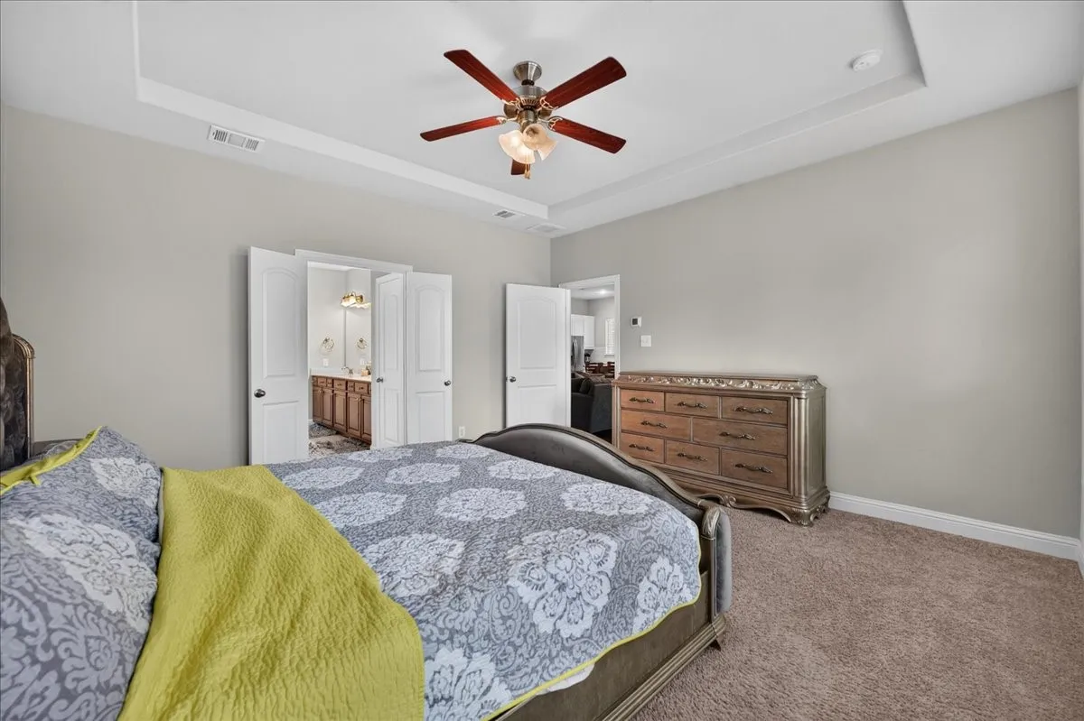 Tray ceiling with a ceiling fan, light gray wall paint, and plush carpeting