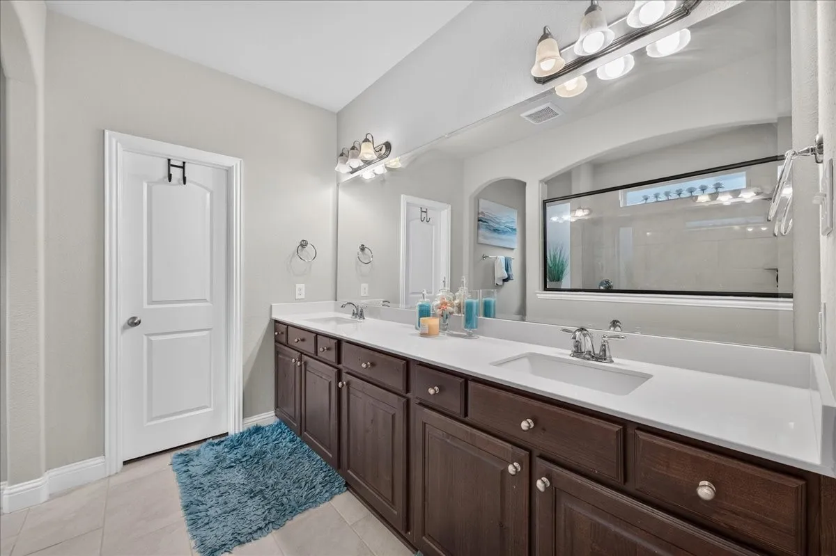 Double vanity with white countertops, dark wood-finish cabinetry, and chrome fixtures