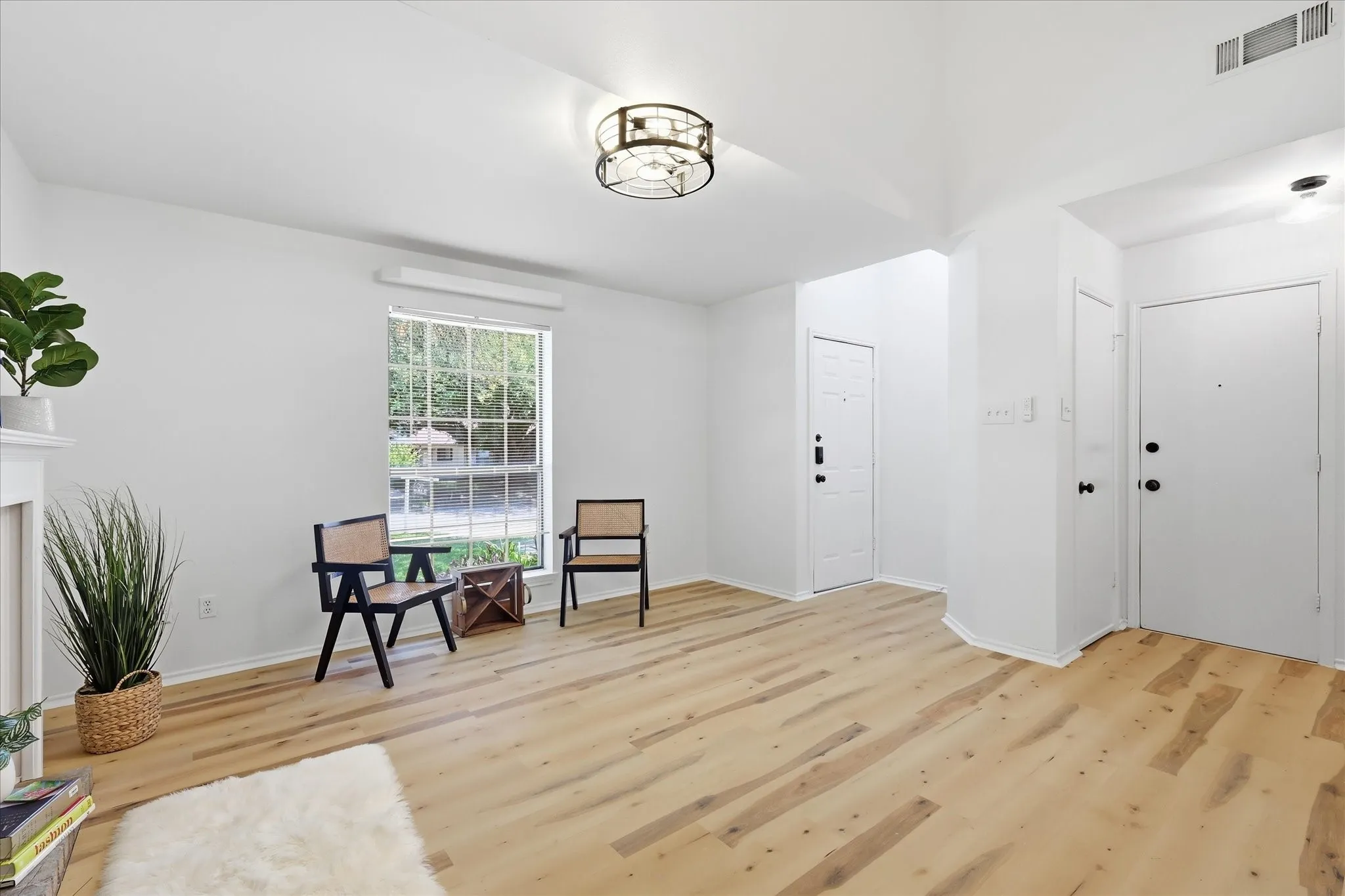Bright interior with wood-finish flooring, white walls, and a contemporary ceiling light fixture