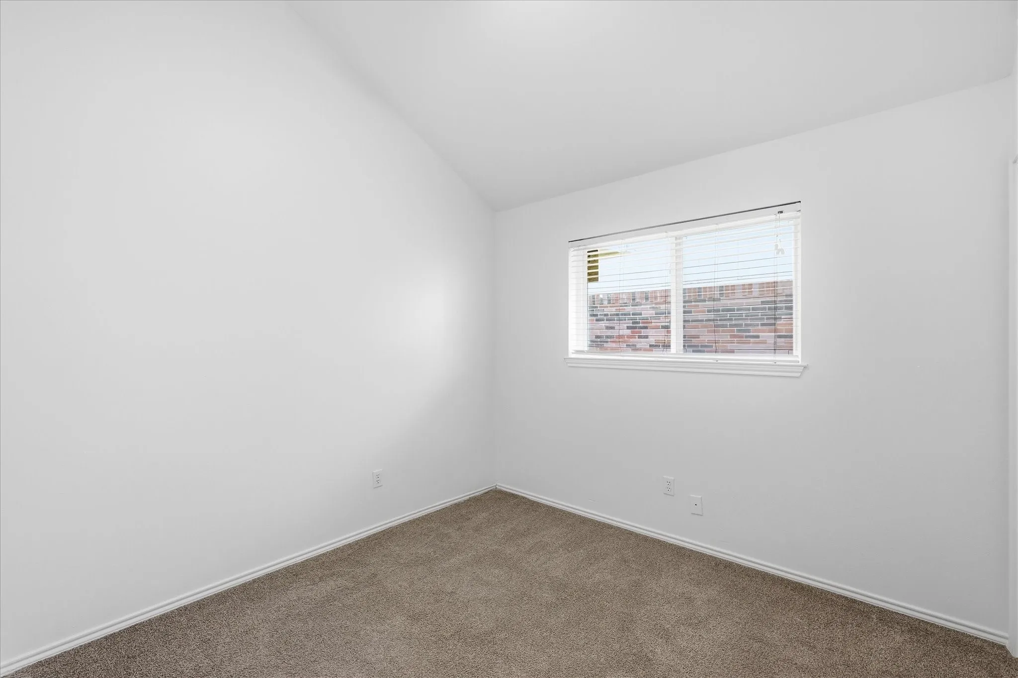 Sloped ceiling, neutral wall tones, carpet flooring, single window with horizontal blinds