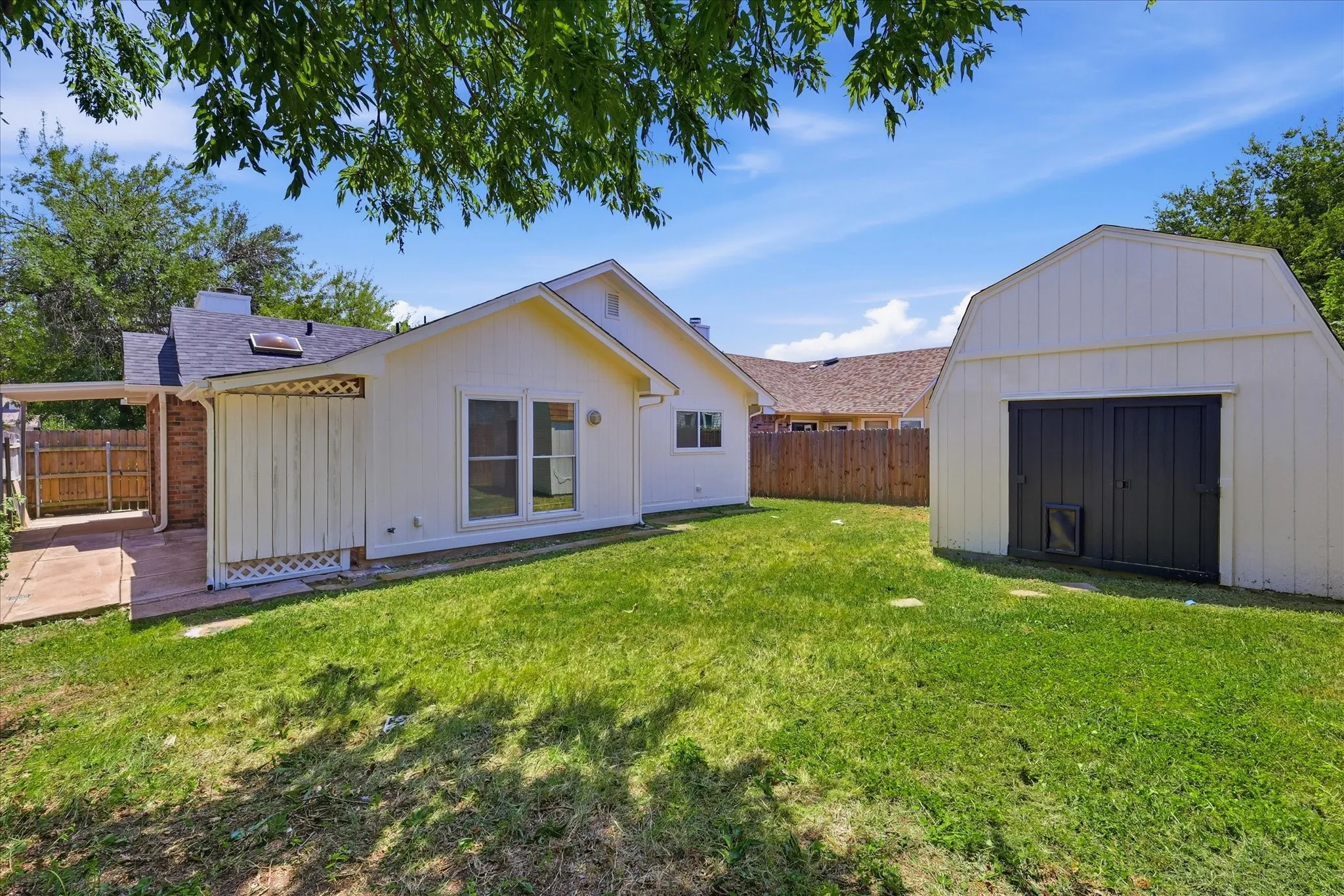 Expansive backyard featuring a detached storage shed, a covered patio, and a privacy fence