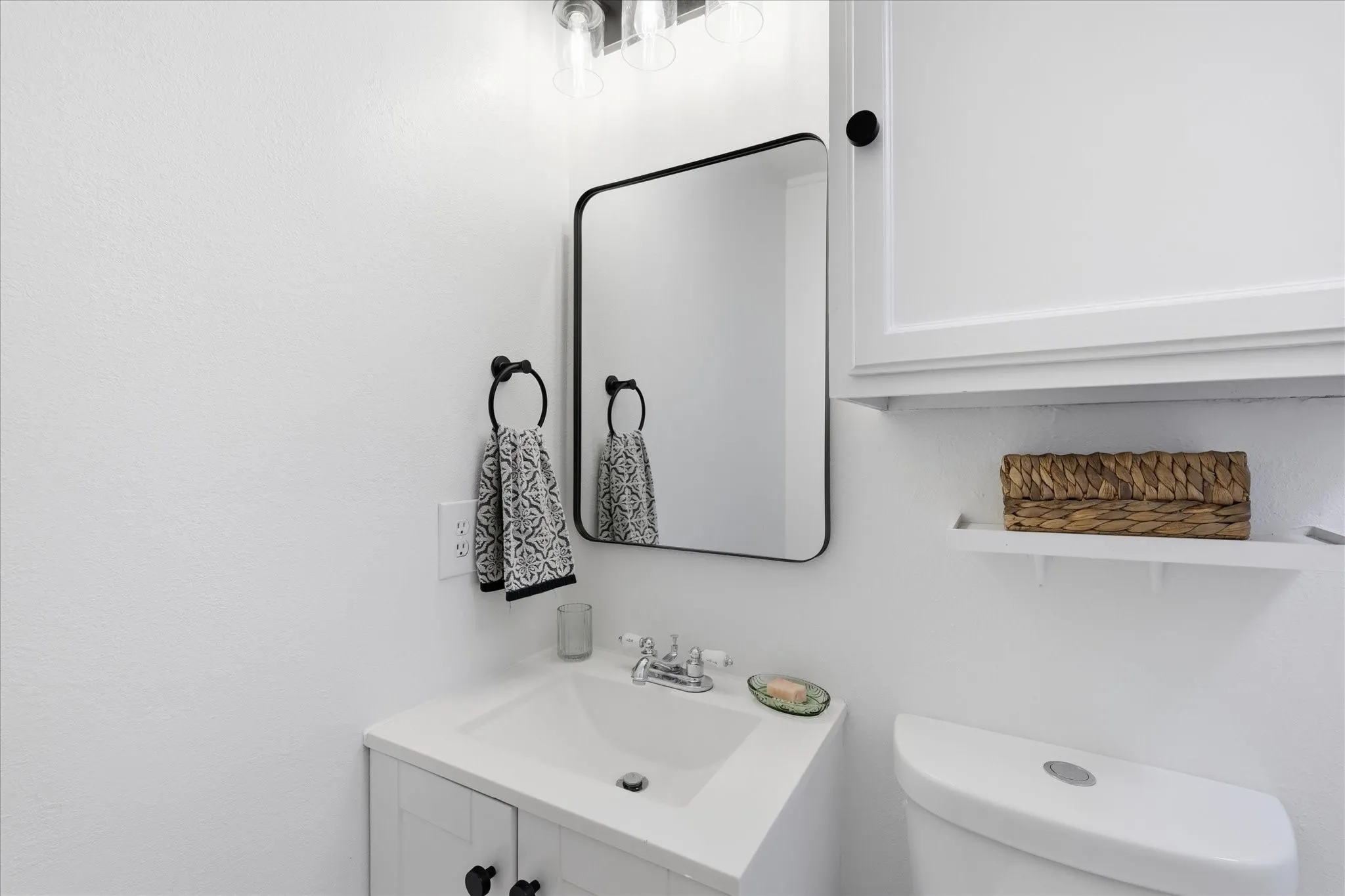 White vanity with an integrated sink, black framed mirror, and chrome faucet