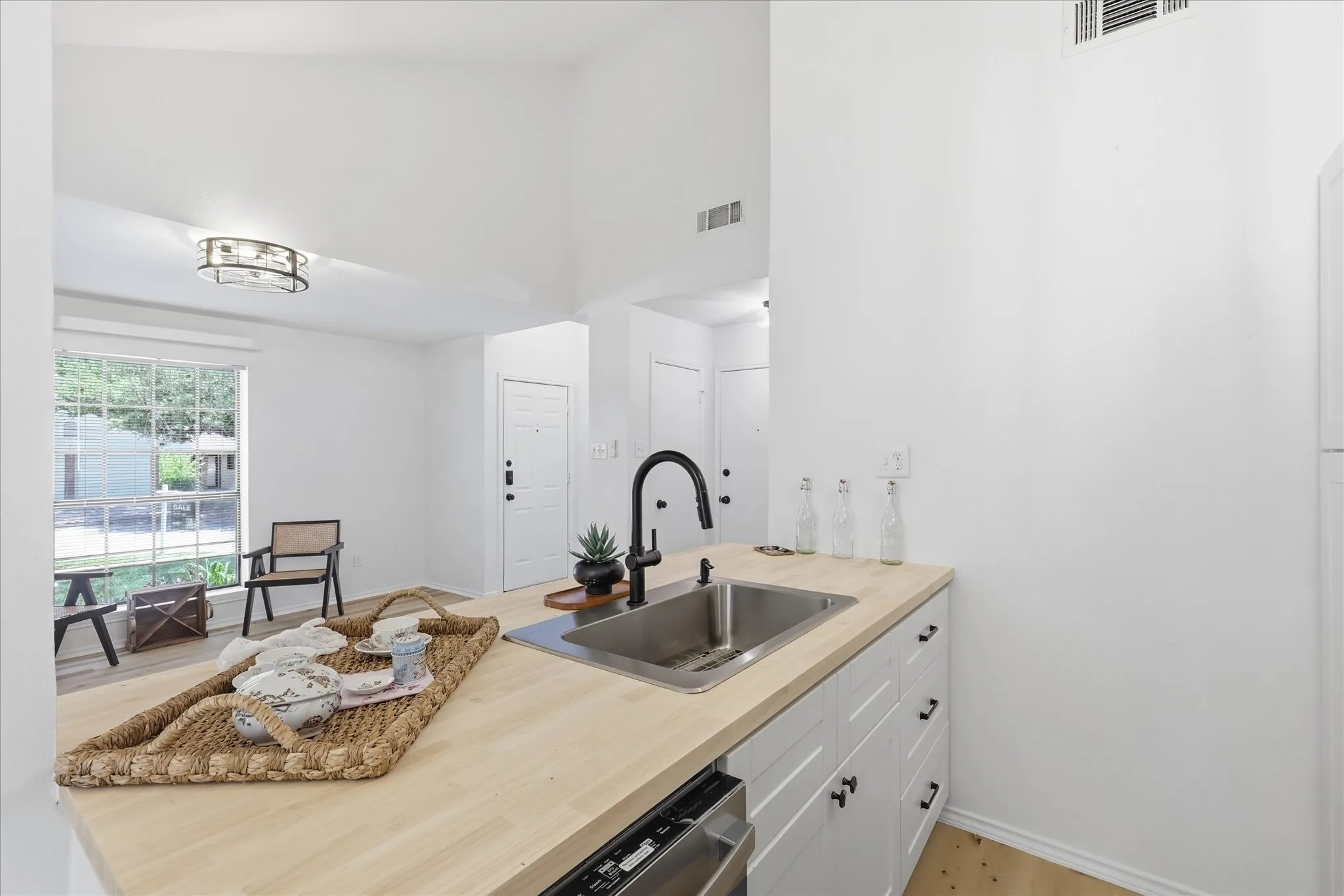 Kitchen counter with wood-finish surface, undermount stainless steel sink, and black gooseneck faucet