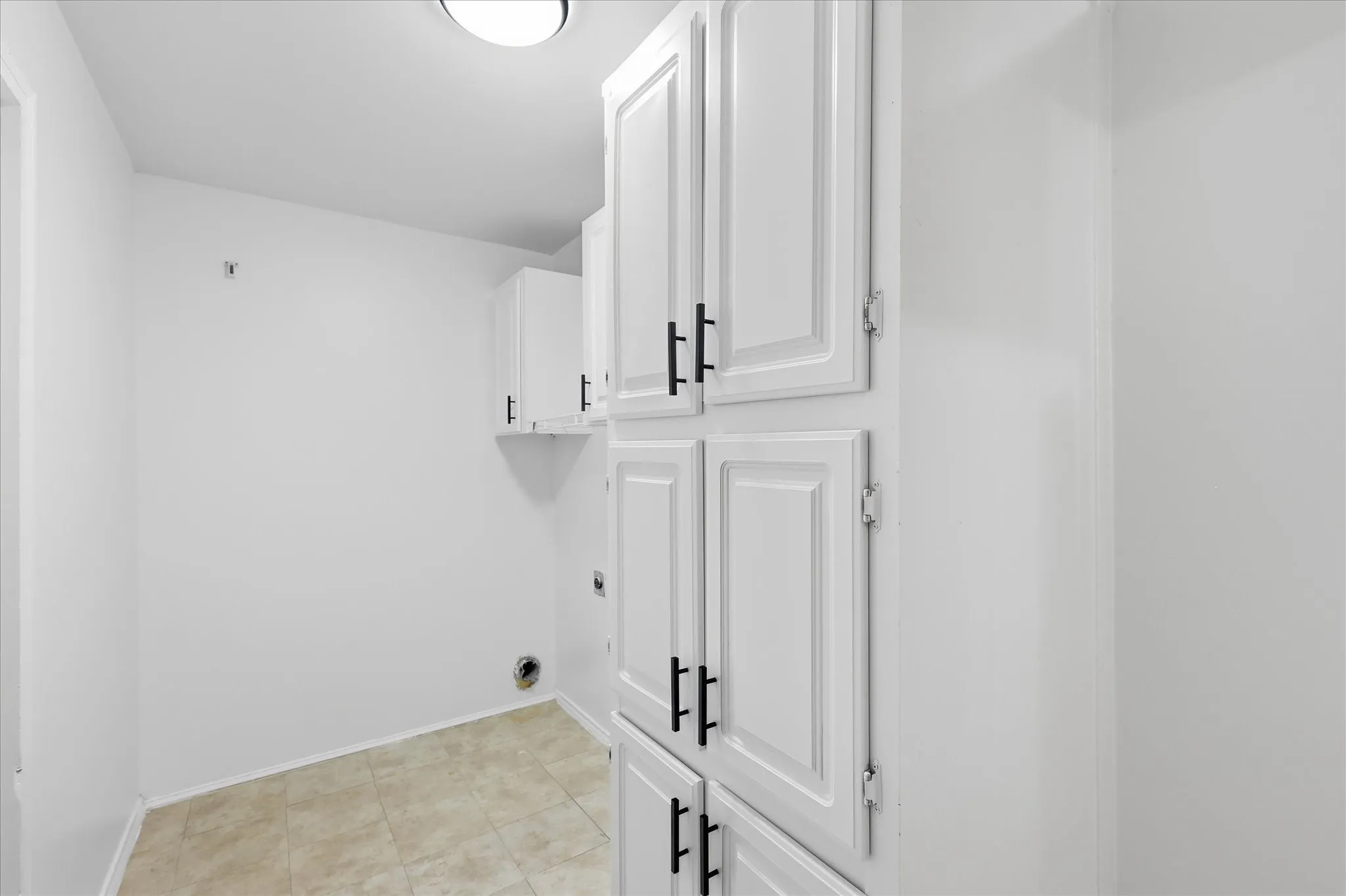 White built-in cabinetry with black hardware, complementing a tile floor and recessed ceiling lighting