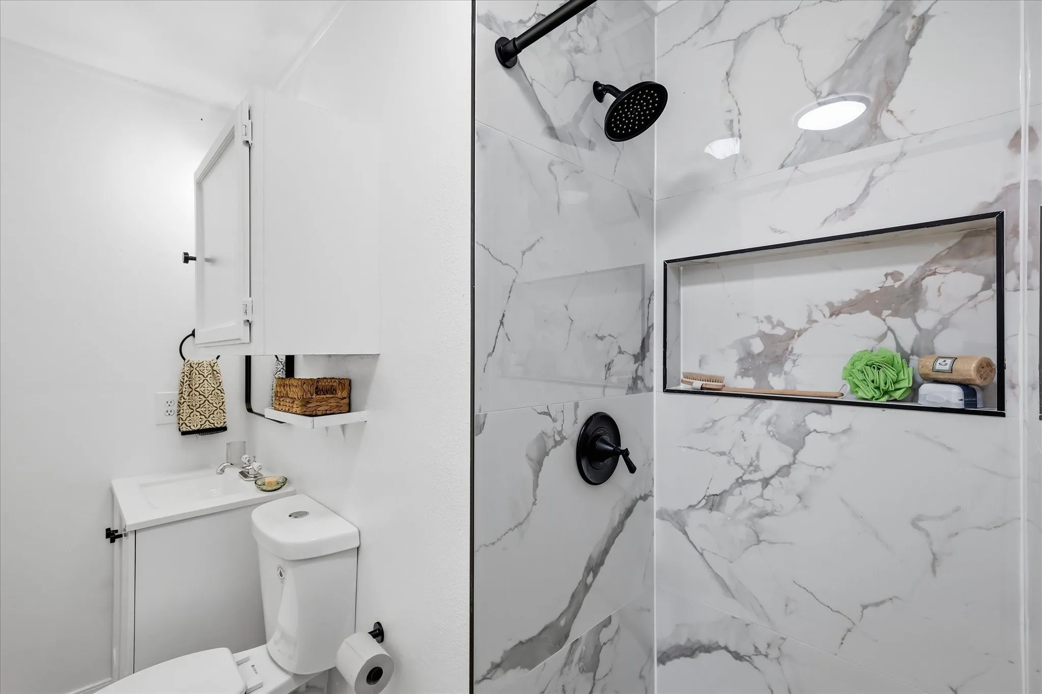 Shower with white marble-look tile, matte black fixtures, and an integrated rectangular niche