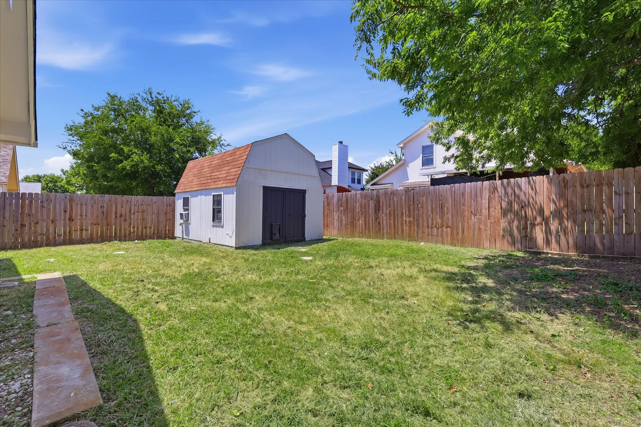Expansive backyard with a storage shed featuring a gambrel roof and a wood privacy fence