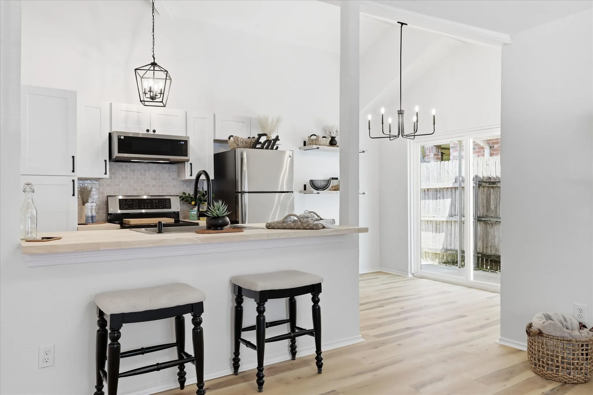 Kitchen with white shaker cabinetry, stainless steel appliances, light wood-finish countertops, and an integrated breakfast bar