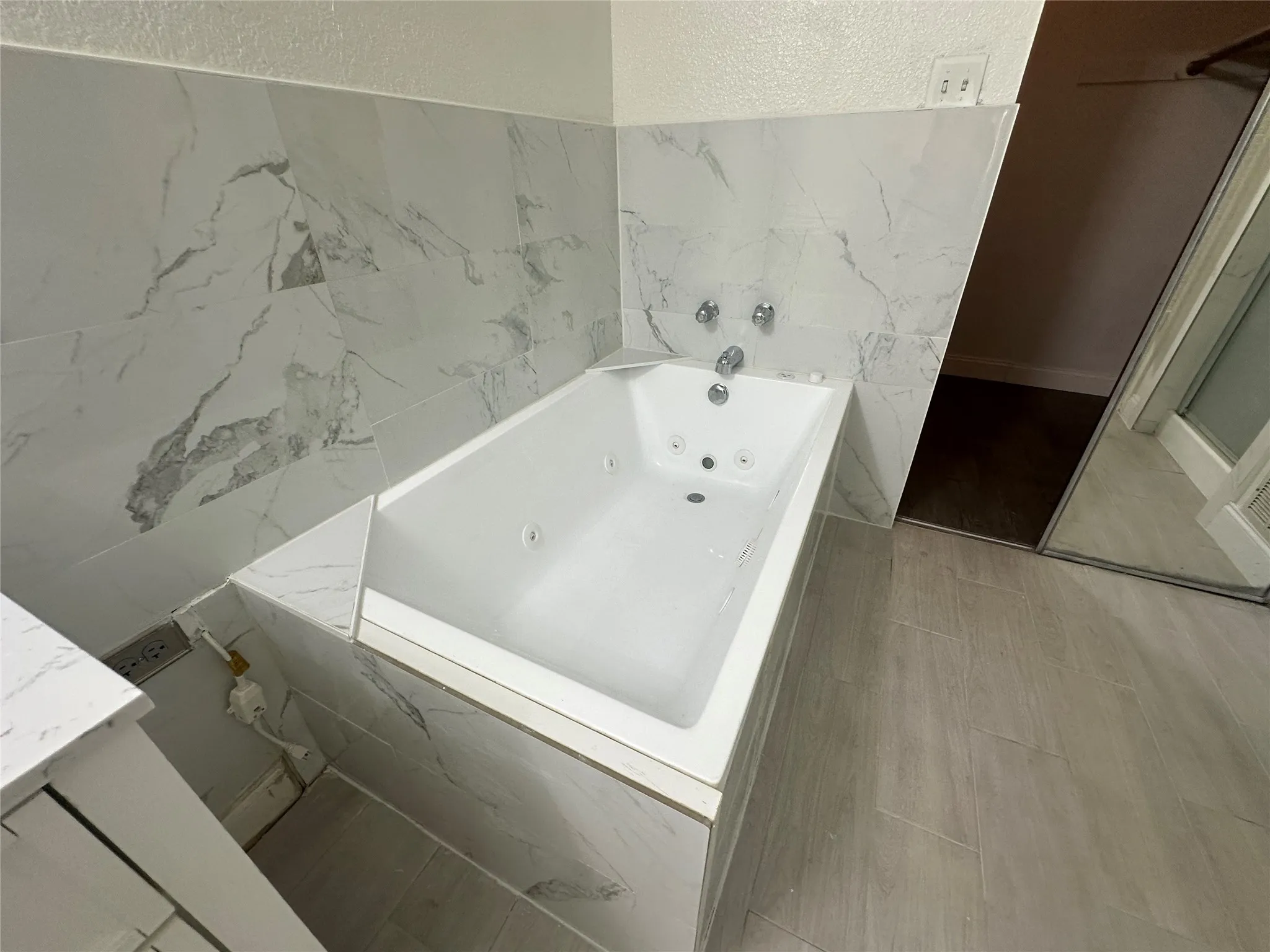 Built-in jetted tub surrounded by large format wall tile