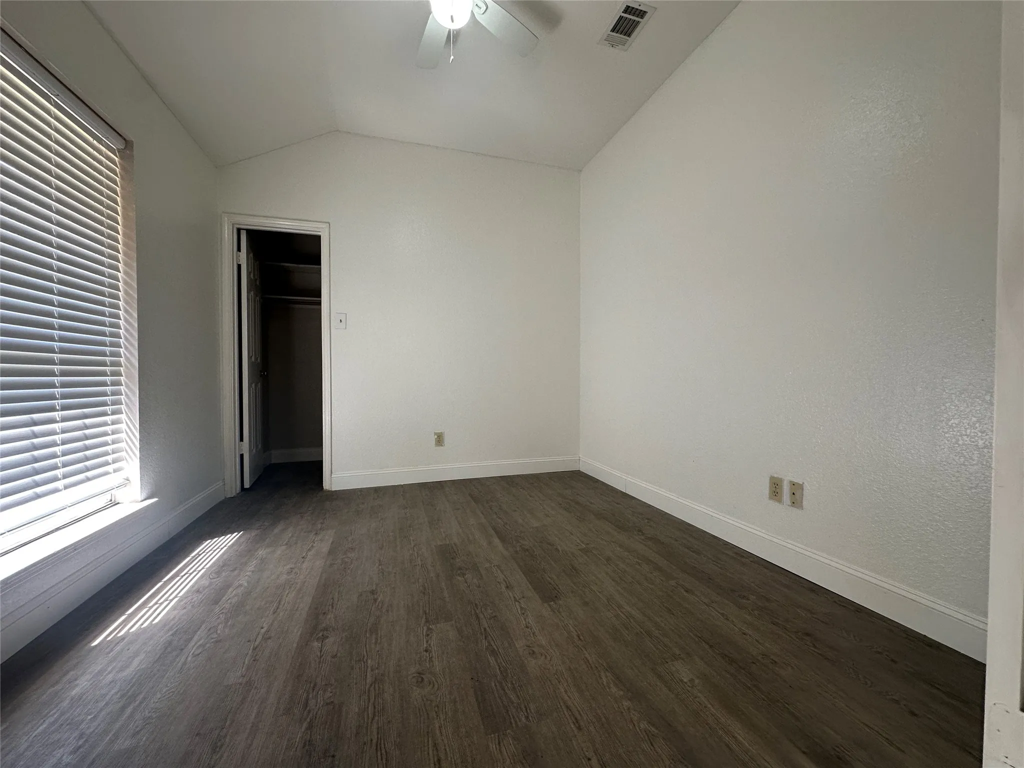 Vaulted ceiling with a ceiling fan, wood-finish flooring, window with blinds, and a built-in closet