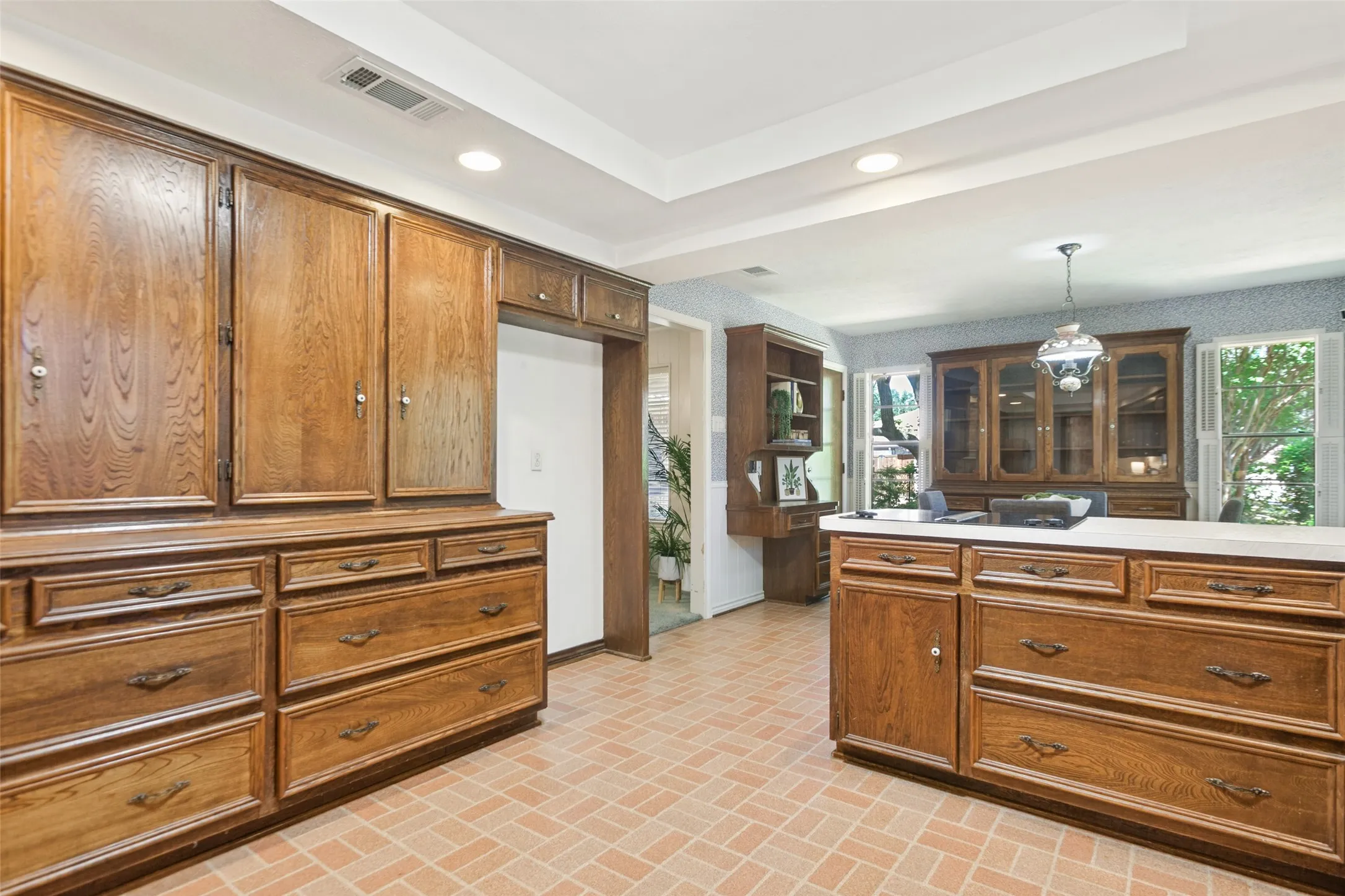 915 Grinnell Dr. - Kitchen featuring a tray ceiling with recessed lighting, a solar tube for additional natural light, traditional wood cabinetry with abundant storage, double ovens, and a large window above the kitchen sink.