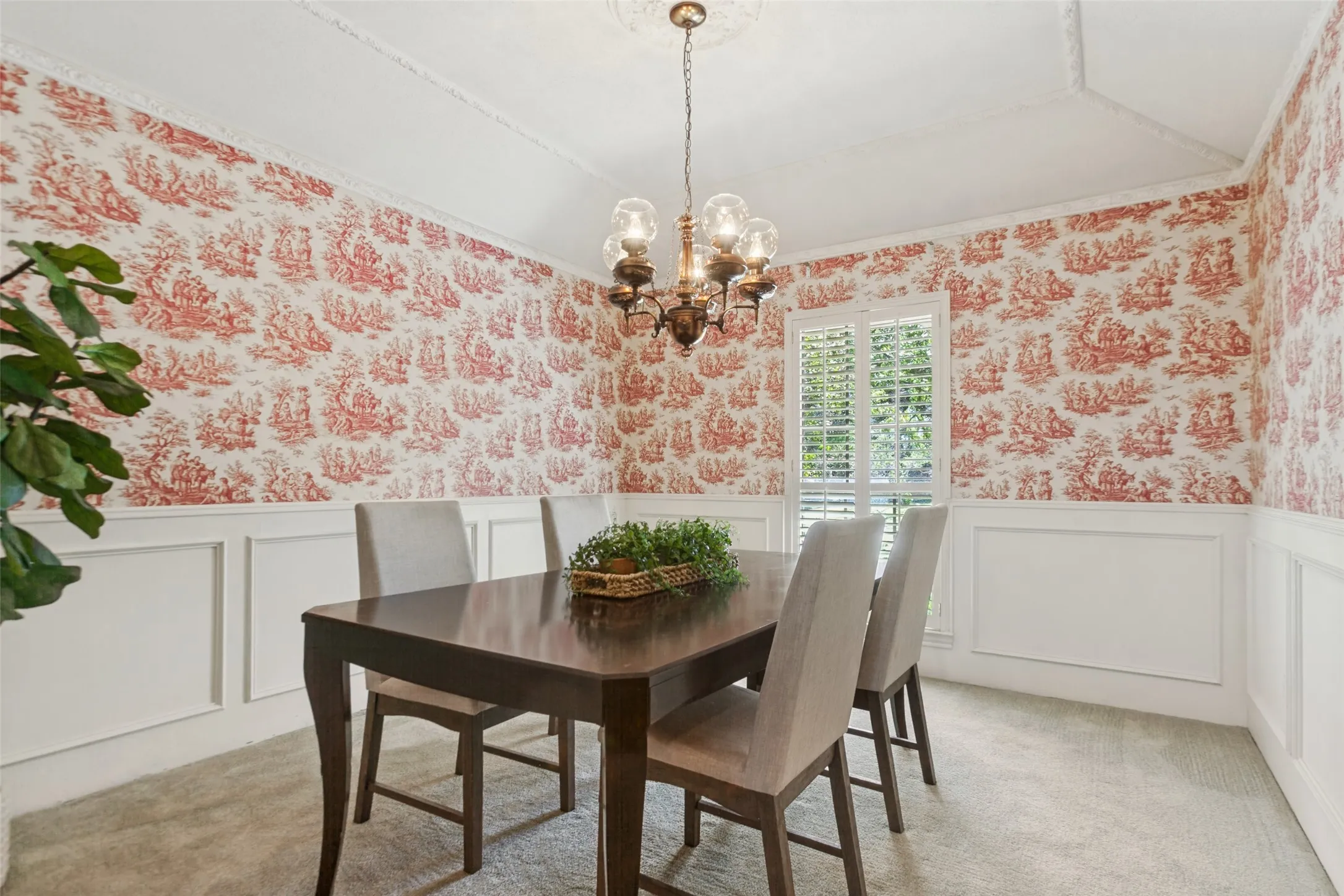 915 Grinnell Dr. - Formal dining area featuring half-height picture-frame wall molding, a gently sloped ceiling with elegant crown molding, and a window accented by a plantation shutter.