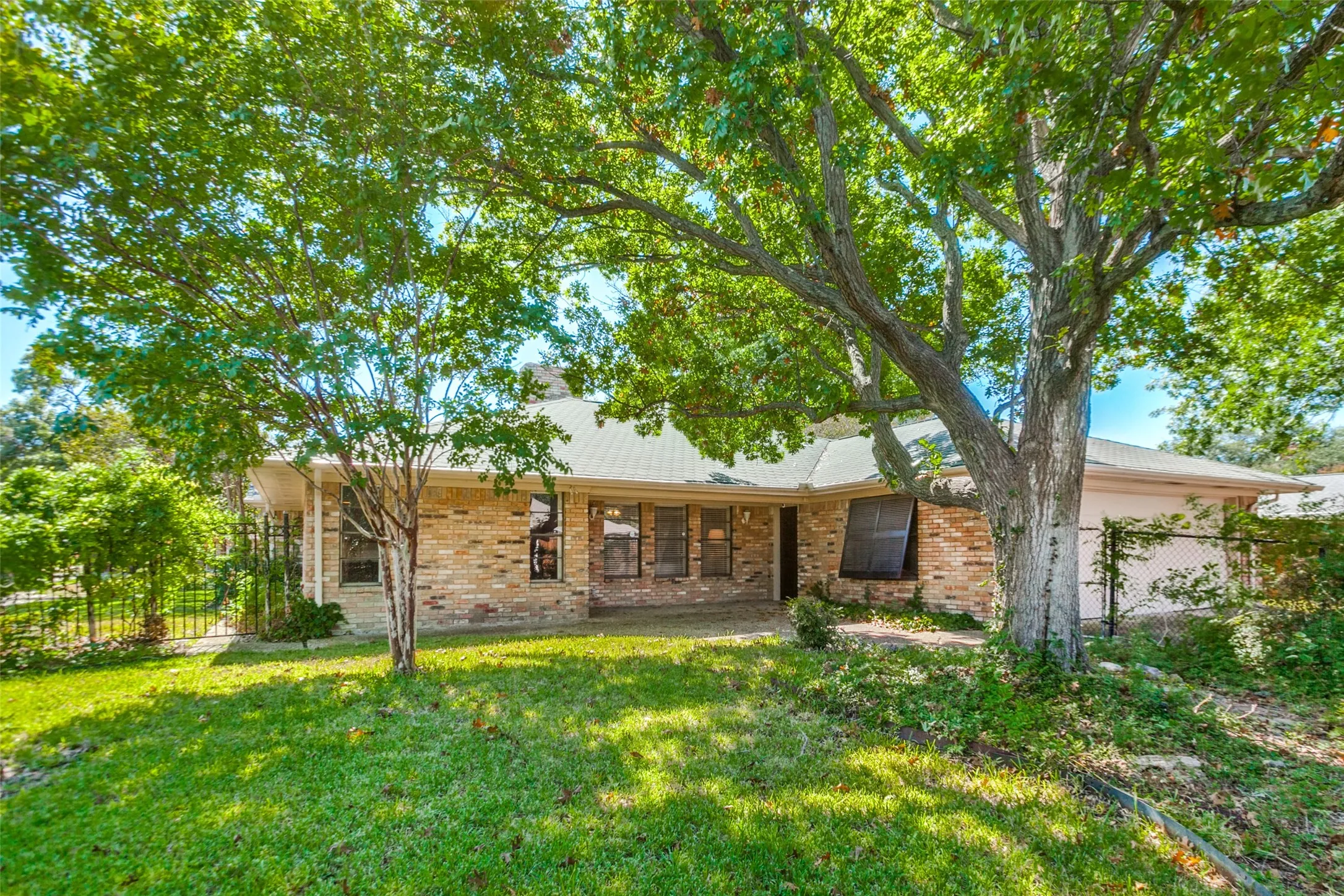 915 Grinnell Dr. - Rear exterior of the home featuring mature trees, a covered back porch, and a private, established backyard setting.