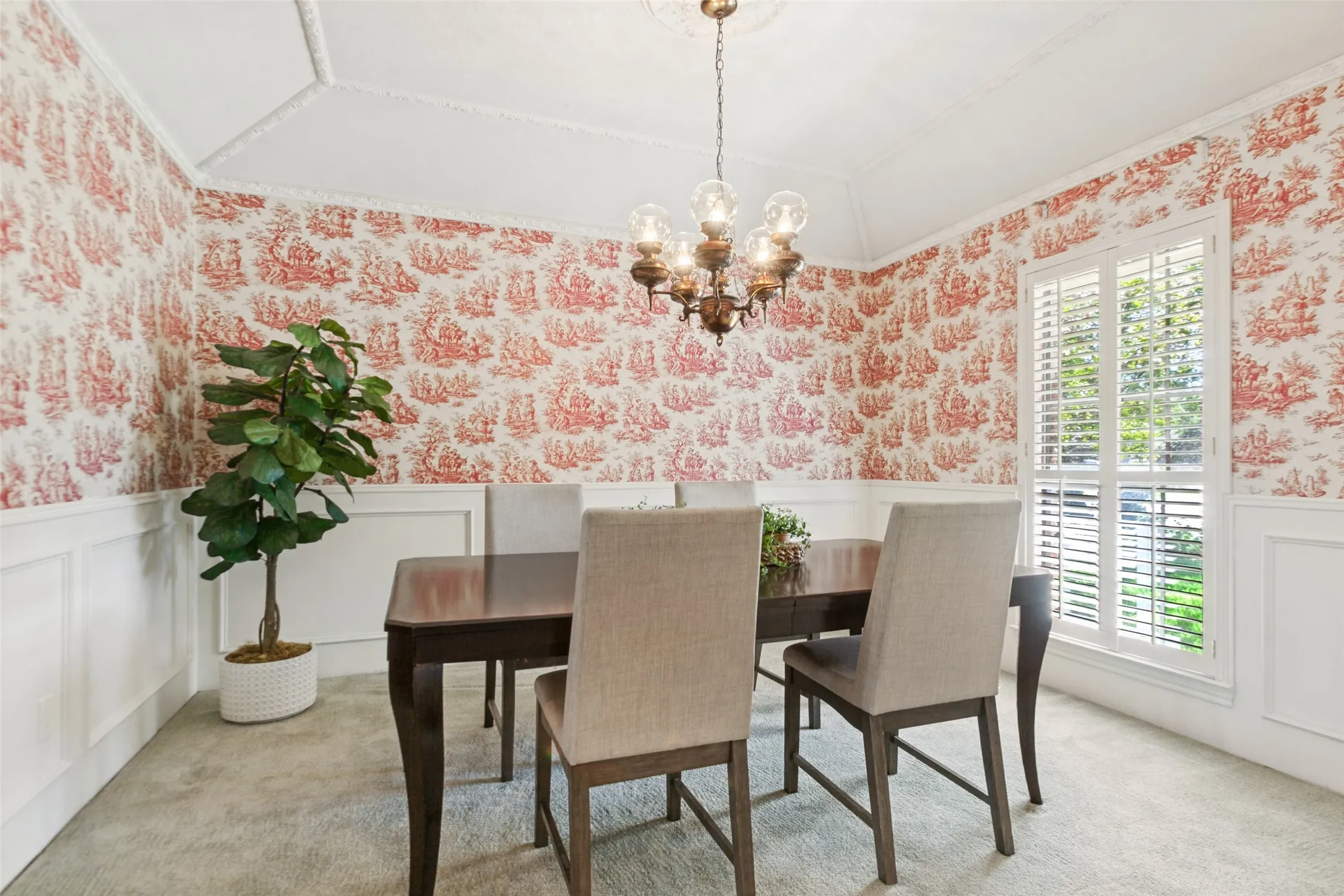 915 Grinnell Dr. - Formal dining area featuring half-height picture-frame wall molding, a gently sloped ceiling with elegant crown molding, and a window accented by a plantation shutter.