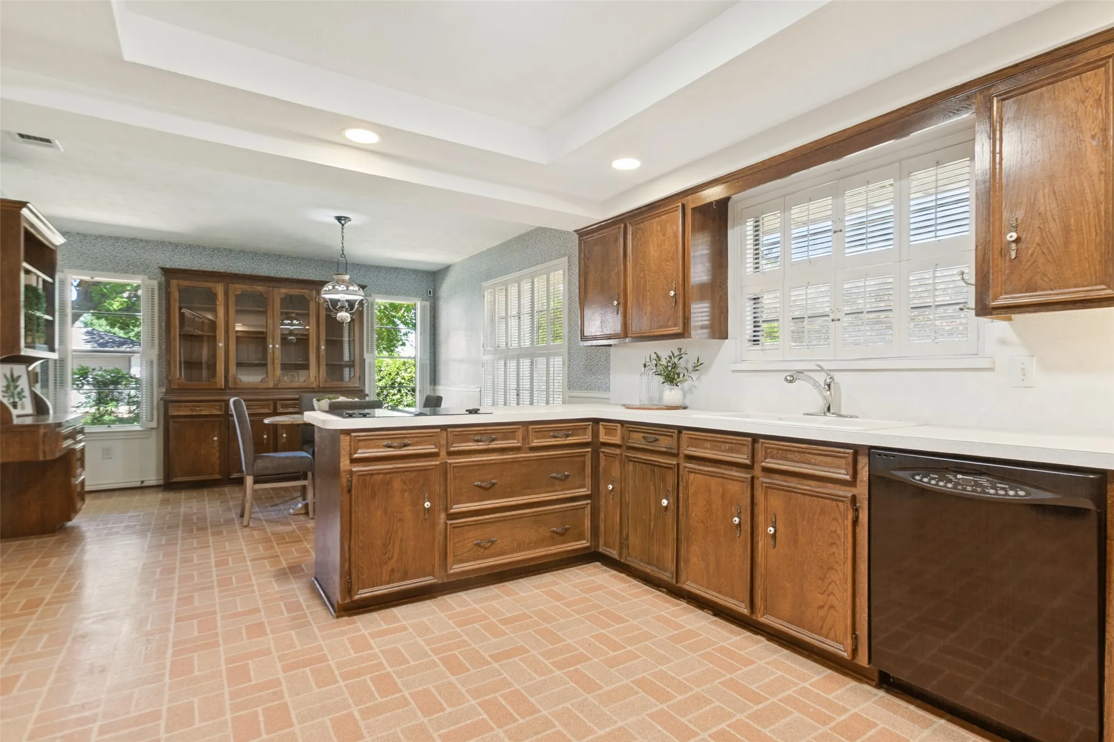 915 Grinnell Dr. - Kitchen featuring a tray ceiling with recessed lighting, a solar tube for additional natural light, traditional wood cabinetry with abundant storage, double ovens, and a large window above the kitchen sink.