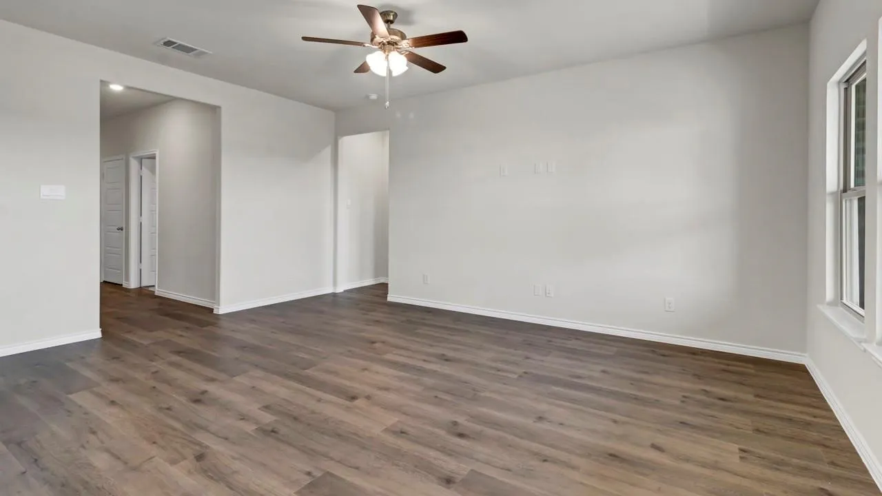 Wood-finish flooring throughout, bright white walls, and a ceiling fan with integrated lighting