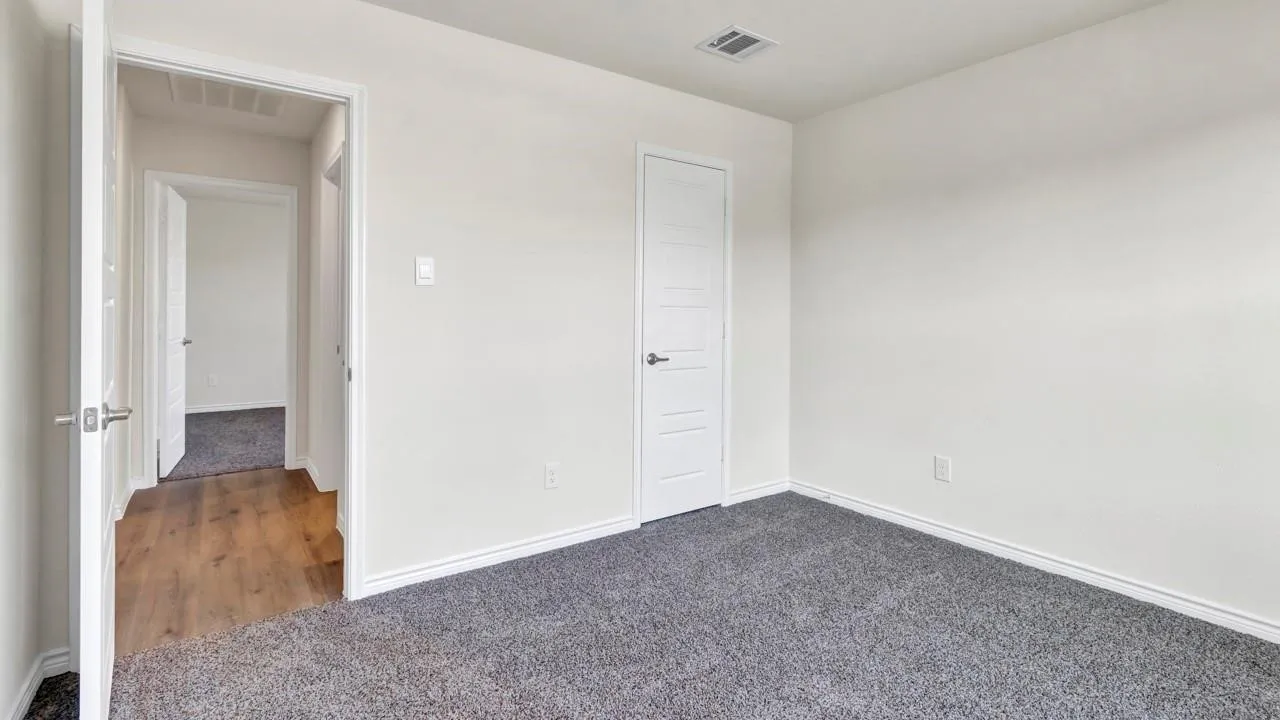 Neutral wall paint, gray carpeting, white trim, and a white interior door