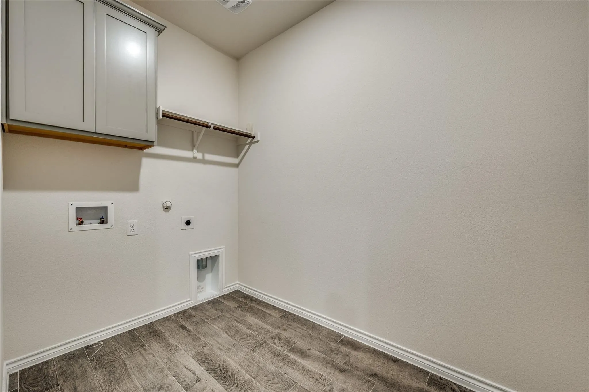 Wood-finish flooring, overhead cabinetry, and a built-in hanging rod