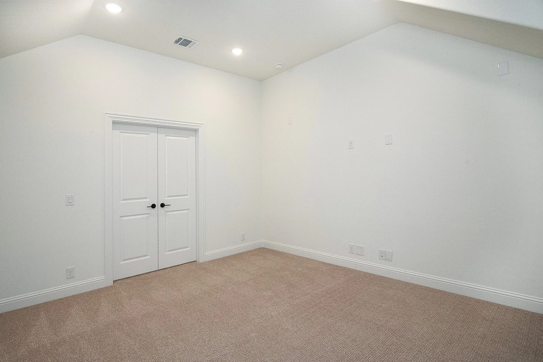 Vaulted ceiling, recessed lighting, double panel doors, neutral carpet, and white trim