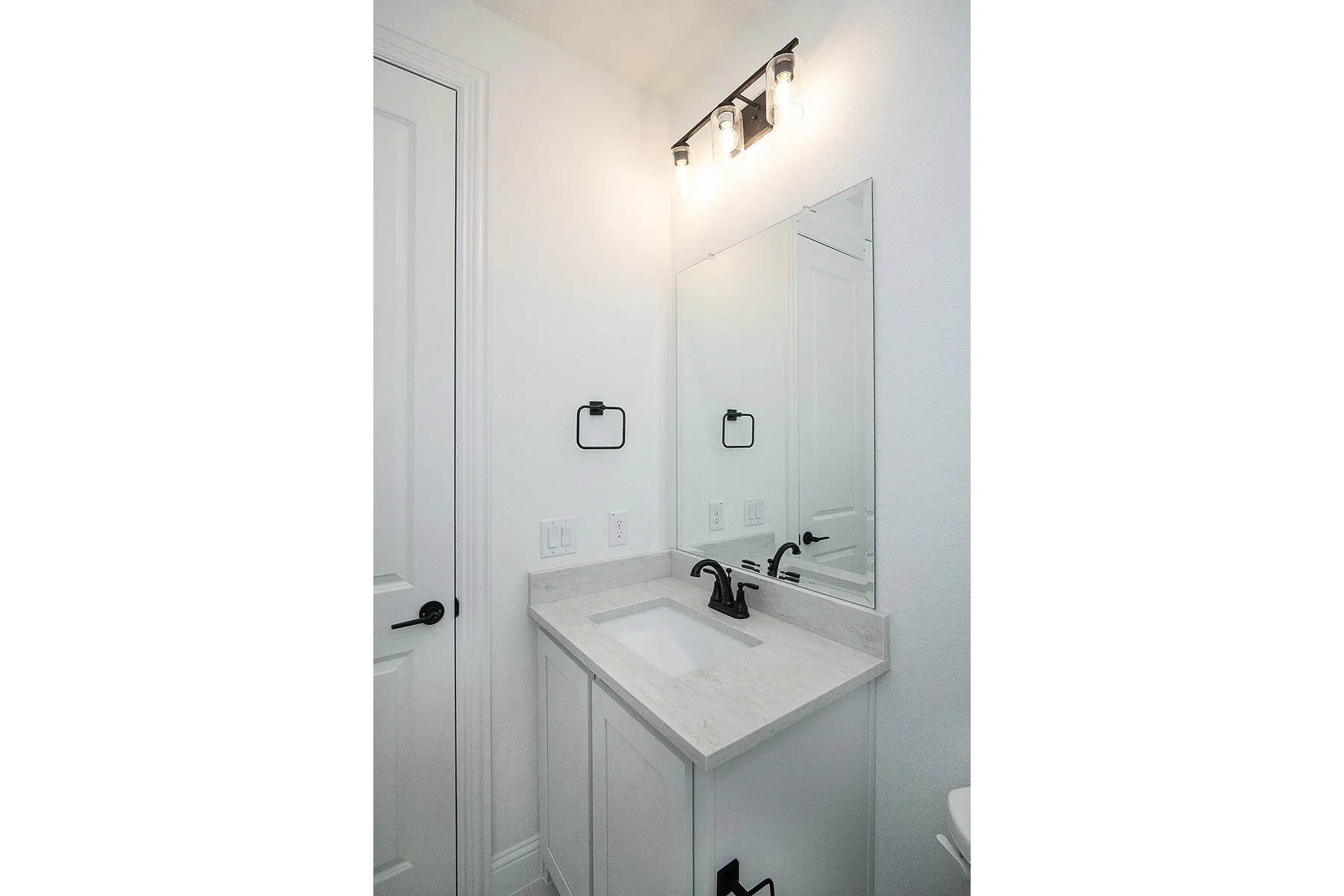 White vanity with a light-toned countertop, integrated sink, and matte black faucet