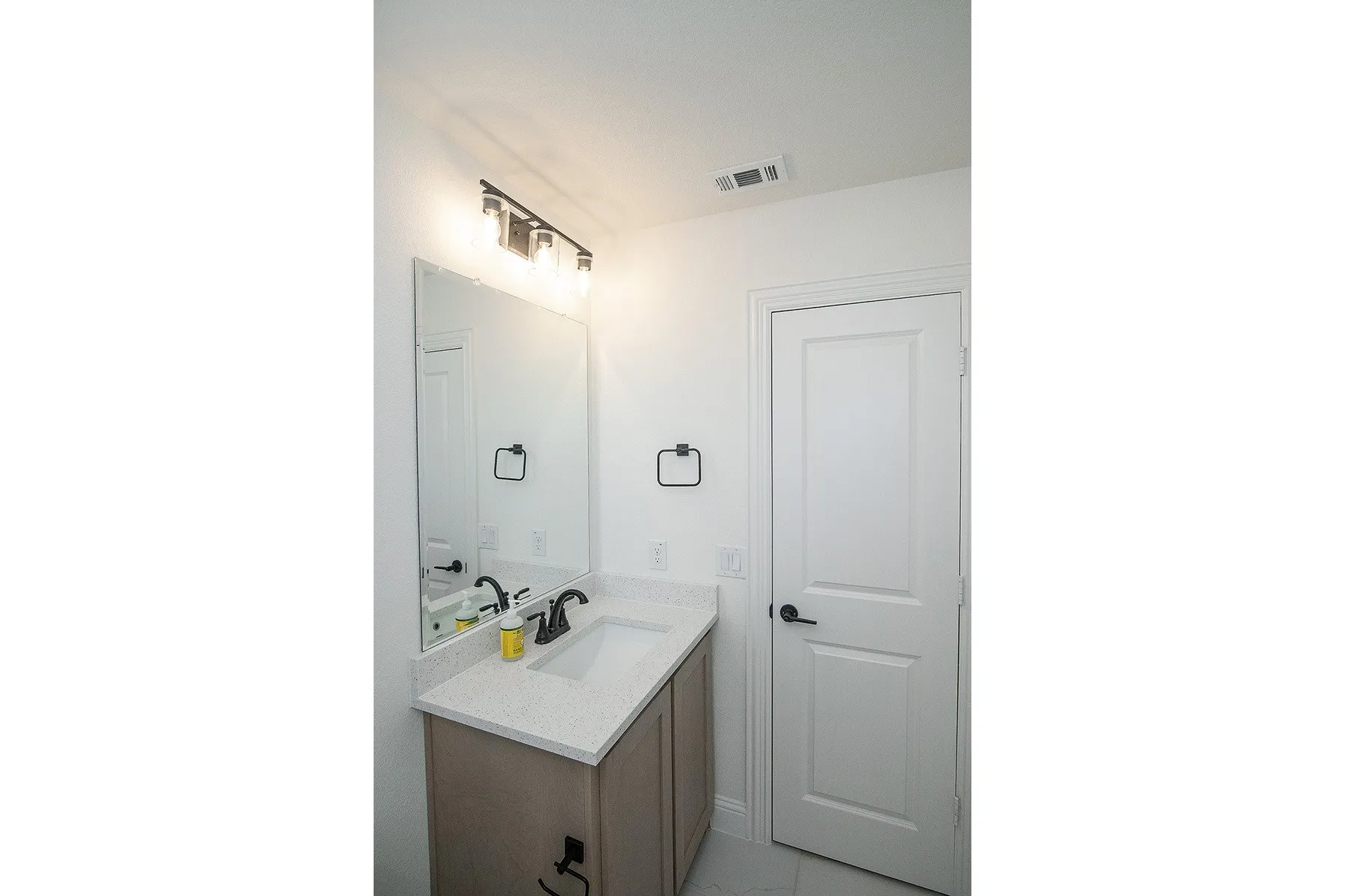 Single vanity with a light-toned cabinet, integrated sink, and light speckled countertop