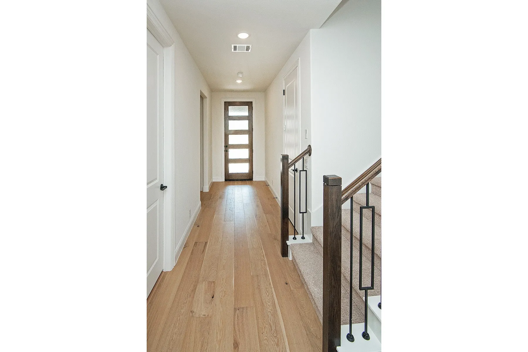 Wood-finish flooring, recessed lighting, and a modern wood door with frosted glass panels