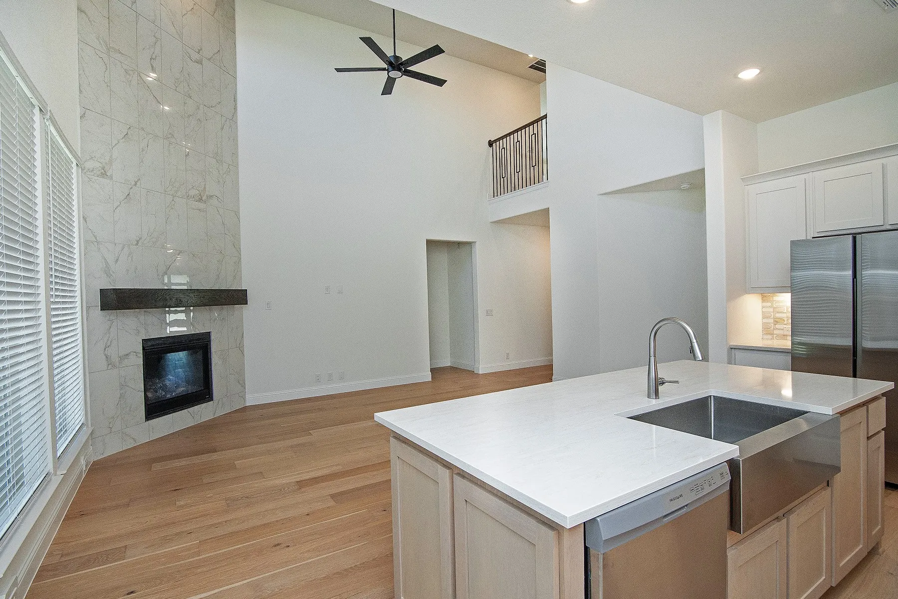 Vaulted ceilings, wood-finish flooring, and a floor-to-ceiling fireplace with a dark mantel