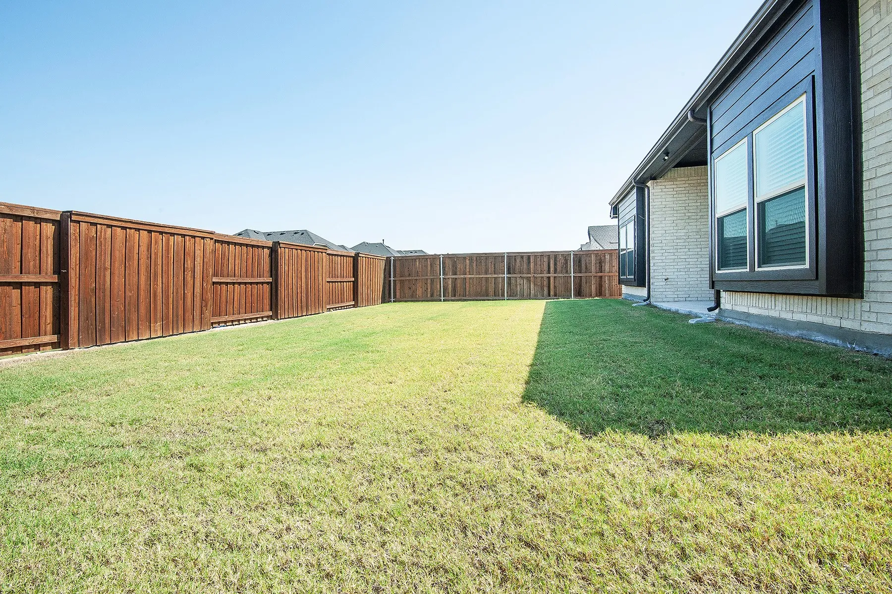 Expansive grass area with a full privacy fence