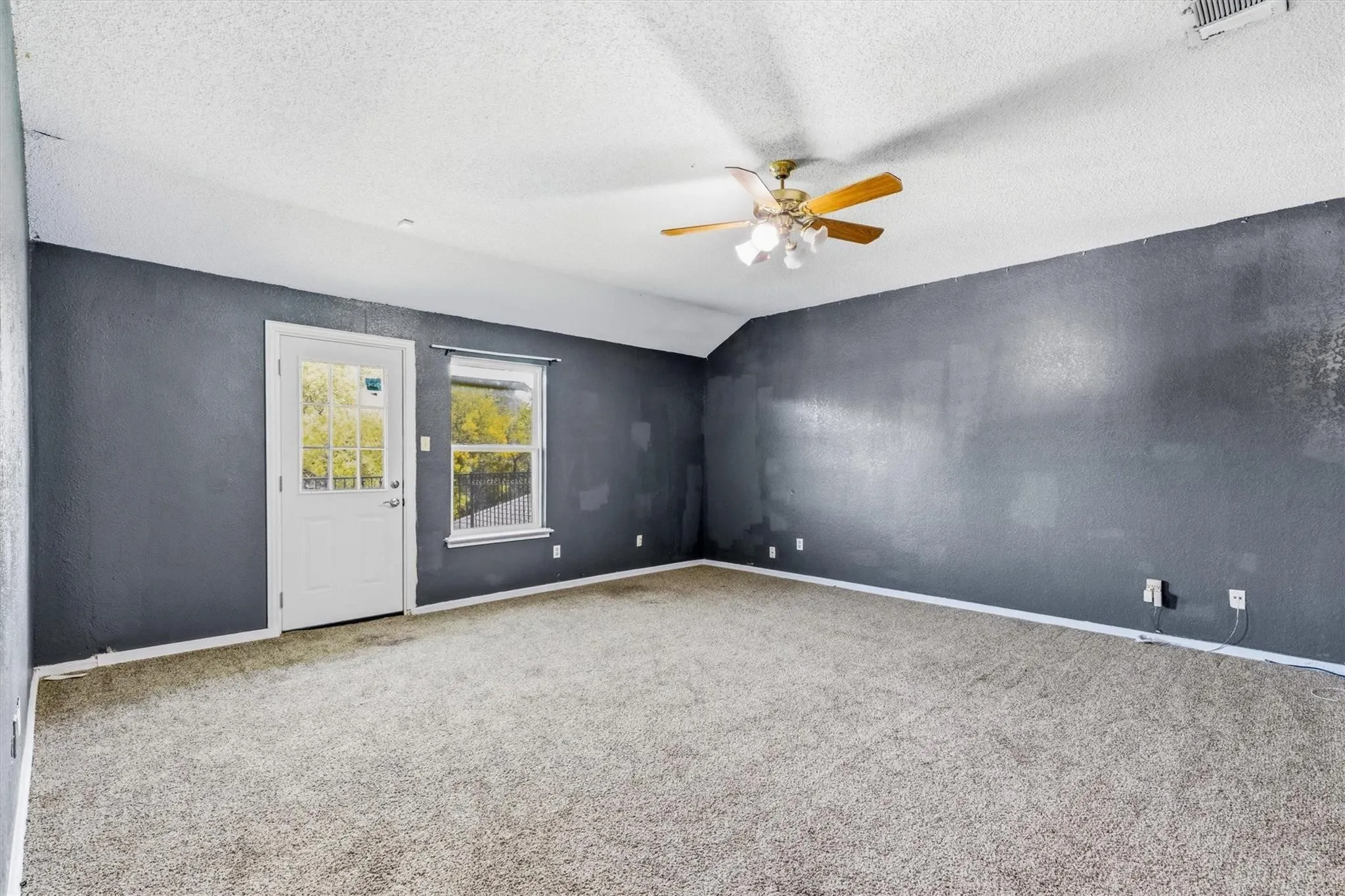 Spacious room featuring a ceiling fan with light fixture, carpeted flooring, and a white paneled door with glass inserts