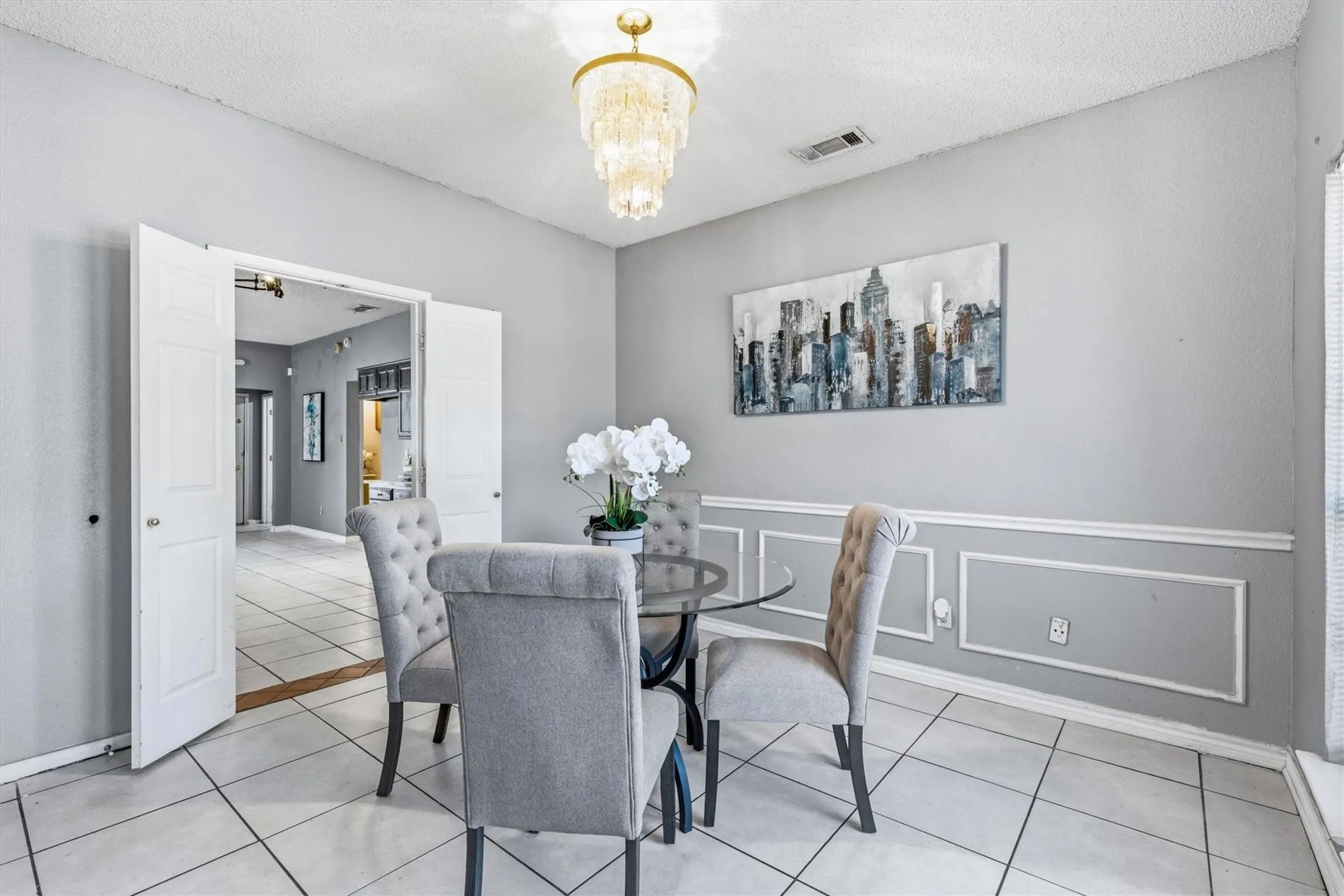 Recessed ceiling light, decorative wall molding, tile flooring, and a tiered chandelier