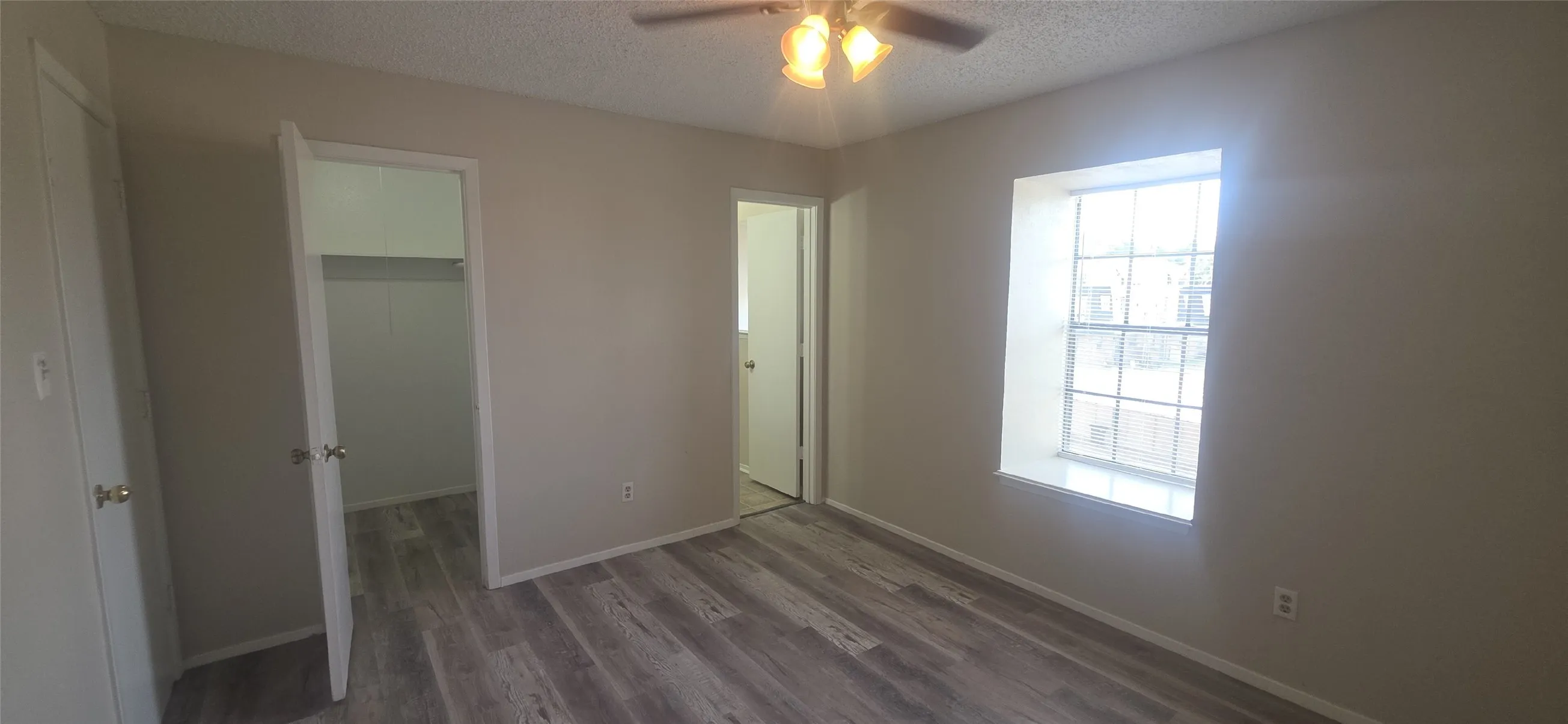 Wood-finish flooring throughout, neutral painted walls, and a ceiling fan with integrated lighting