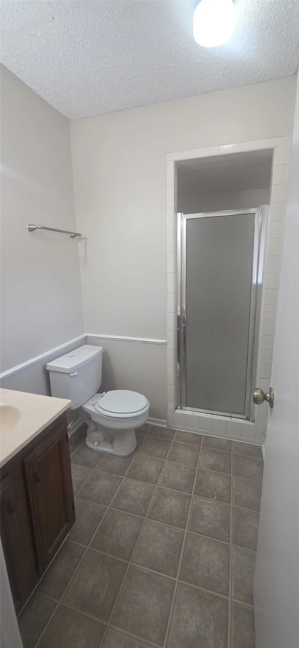 Bathroom featuring a vanity with dark wood-finish cabinetry, light-toned countertop, and square floor tiles