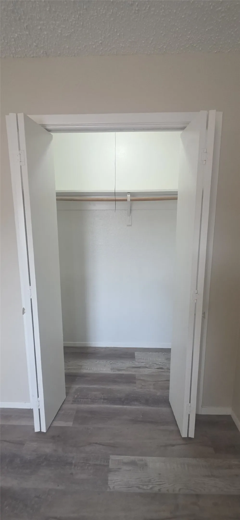 Built-in closet featuring bi-fold doors, a single clothes rod, and wood-finish flooring