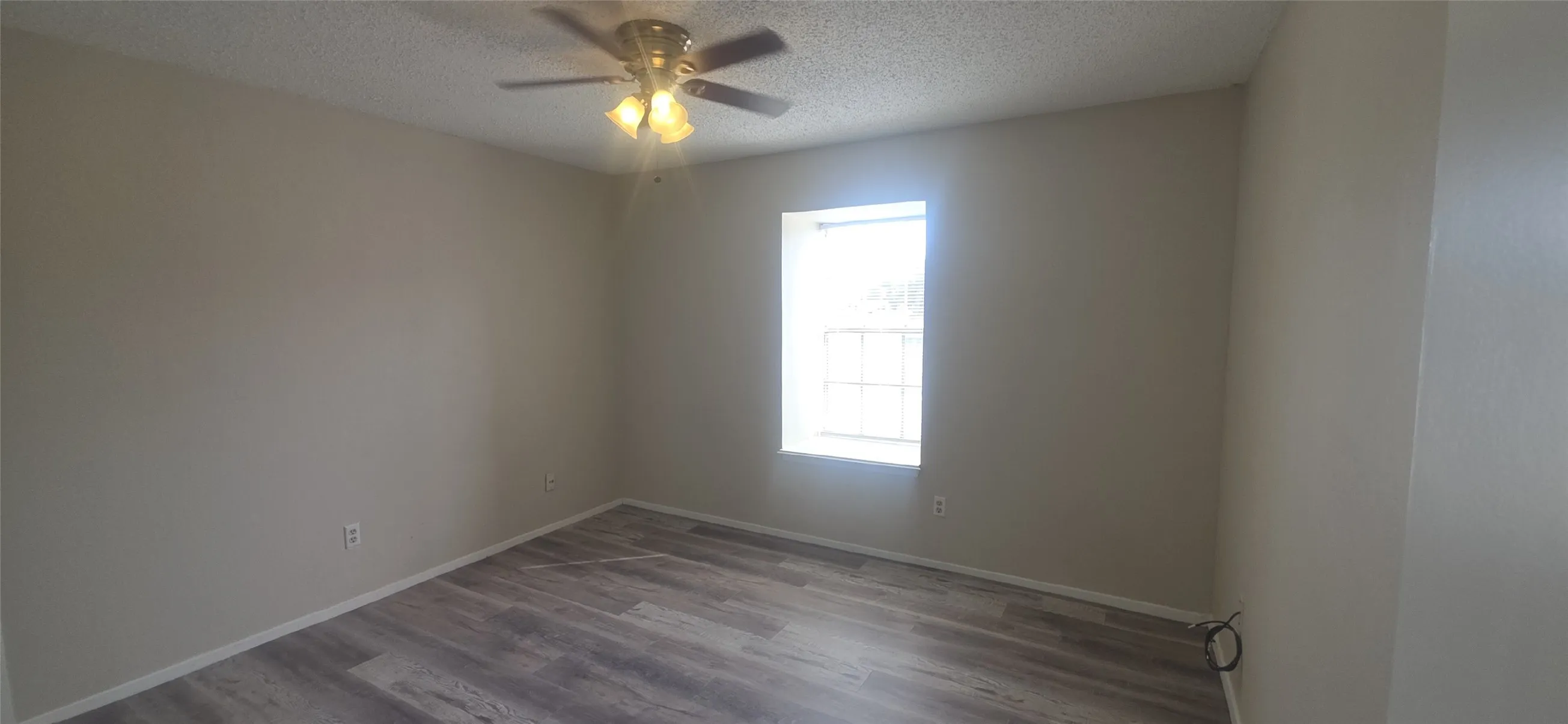 Neutral tone walls, wood-finish flooring, and a ceiling fan with integrated lighting