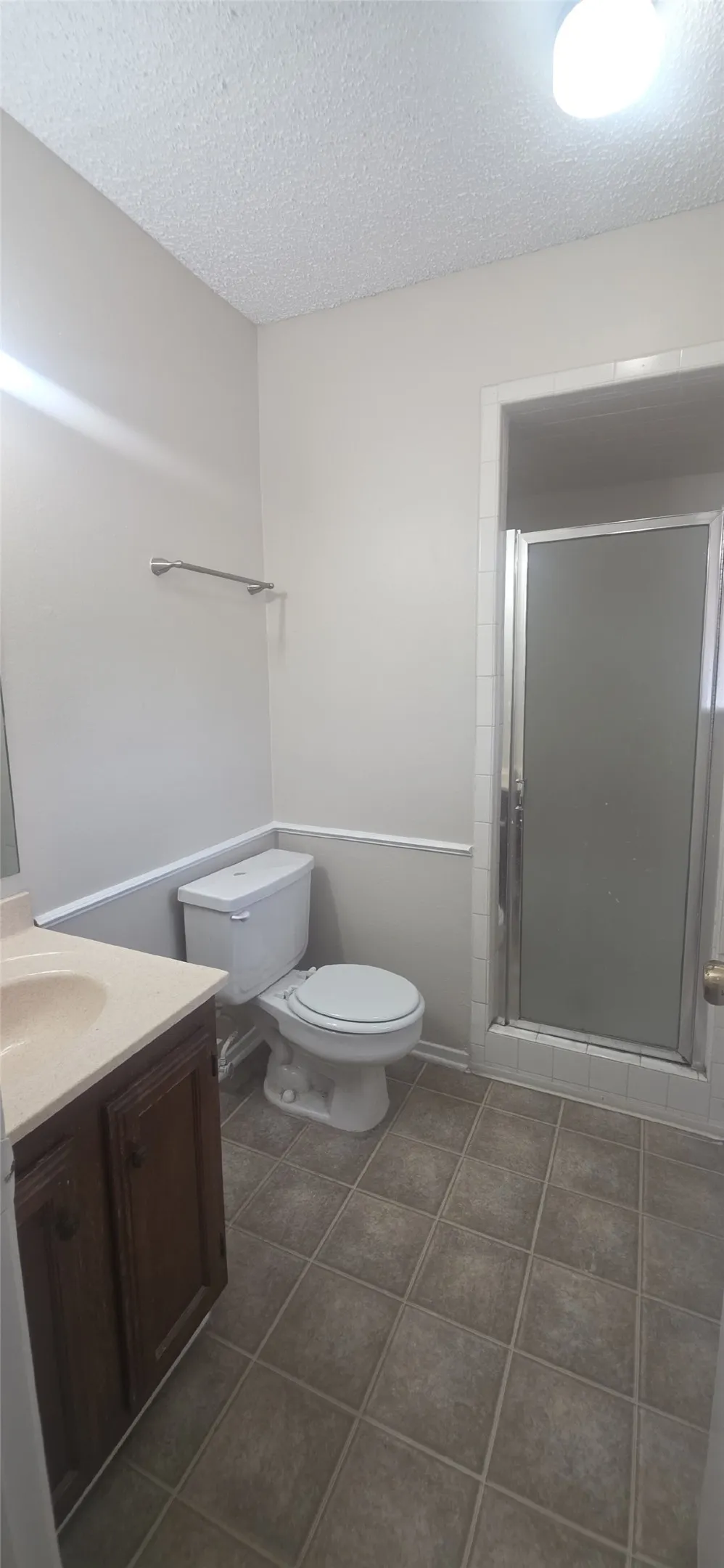 Bathroom featuring a shower with a sliding glass door, a toilet, and a vanity with a light-colored countertop