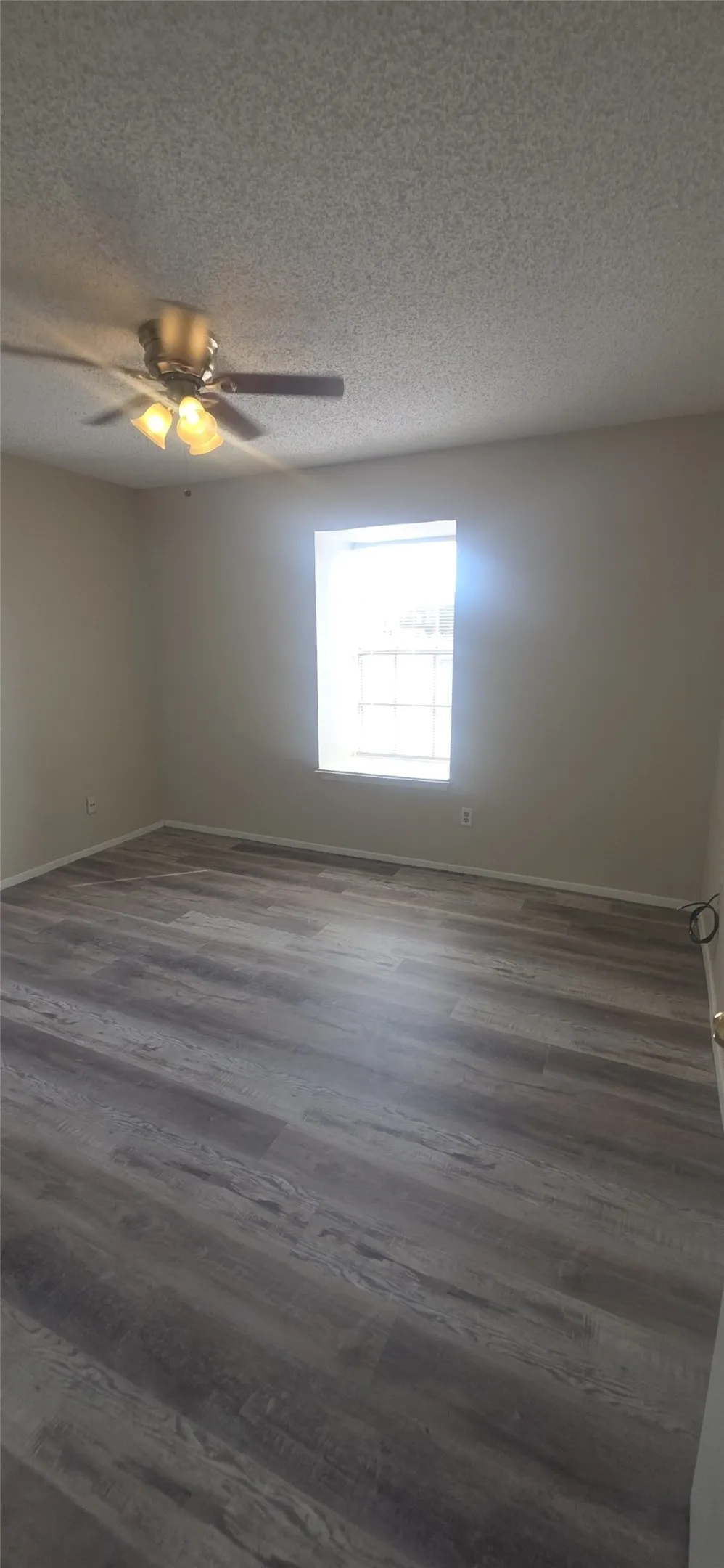 Wood-finish flooring with a ceiling fan and overhead lighting