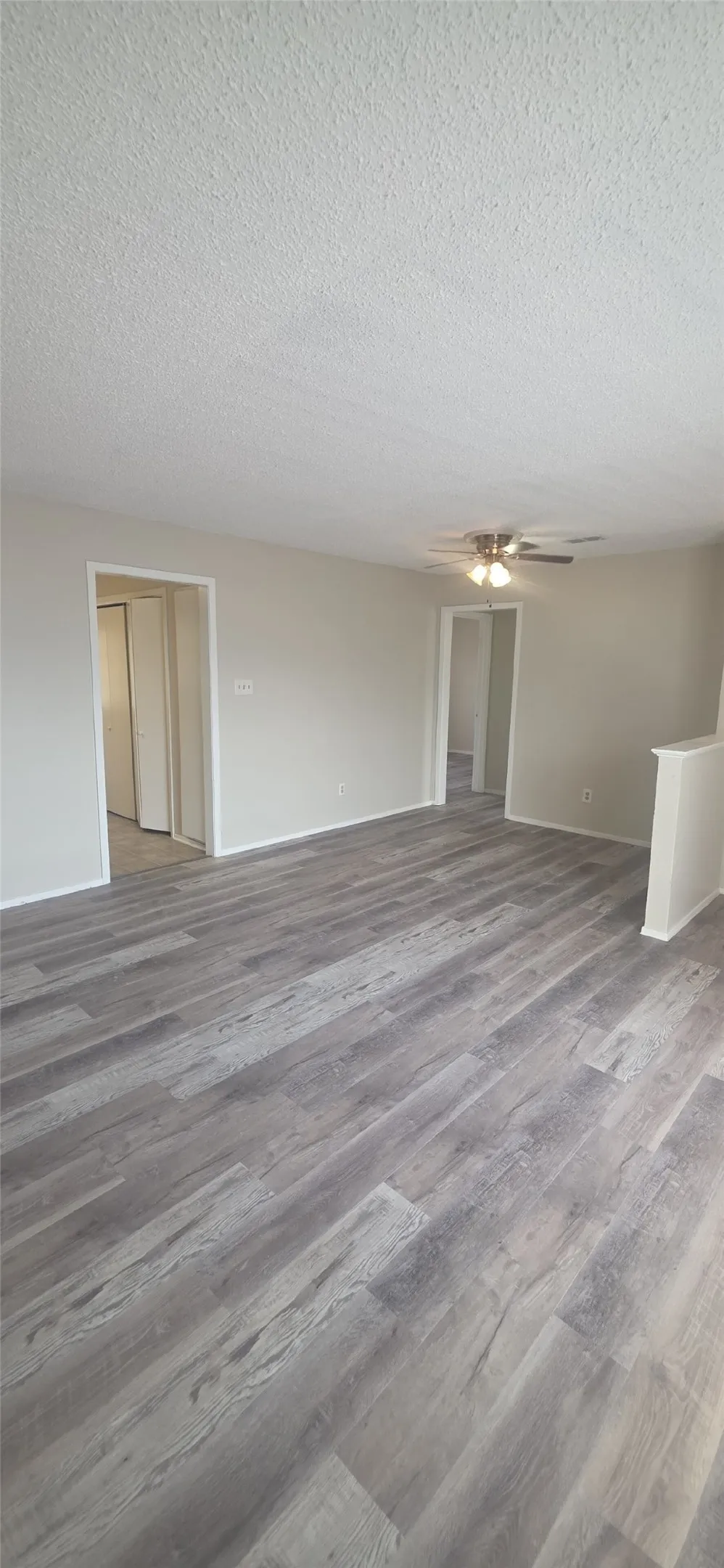 Wood-finish flooring throughout, ceiling fan with light fixture, neutral wall paint, and white trim