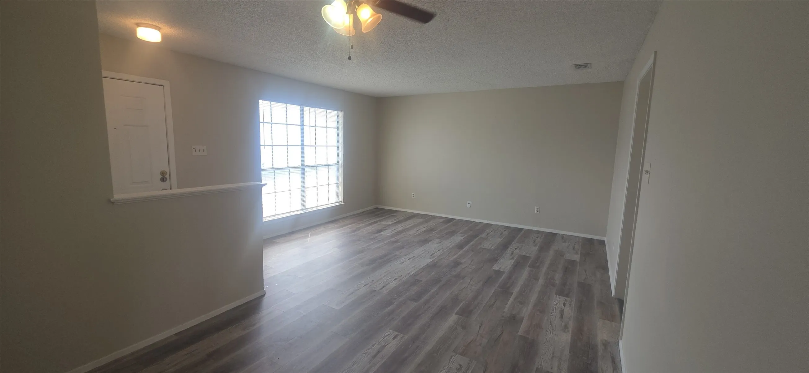 Wood-finish flooring, neutral wall tones, multi-pane window, ceiling fan with integrated lighting, and recessed lighting